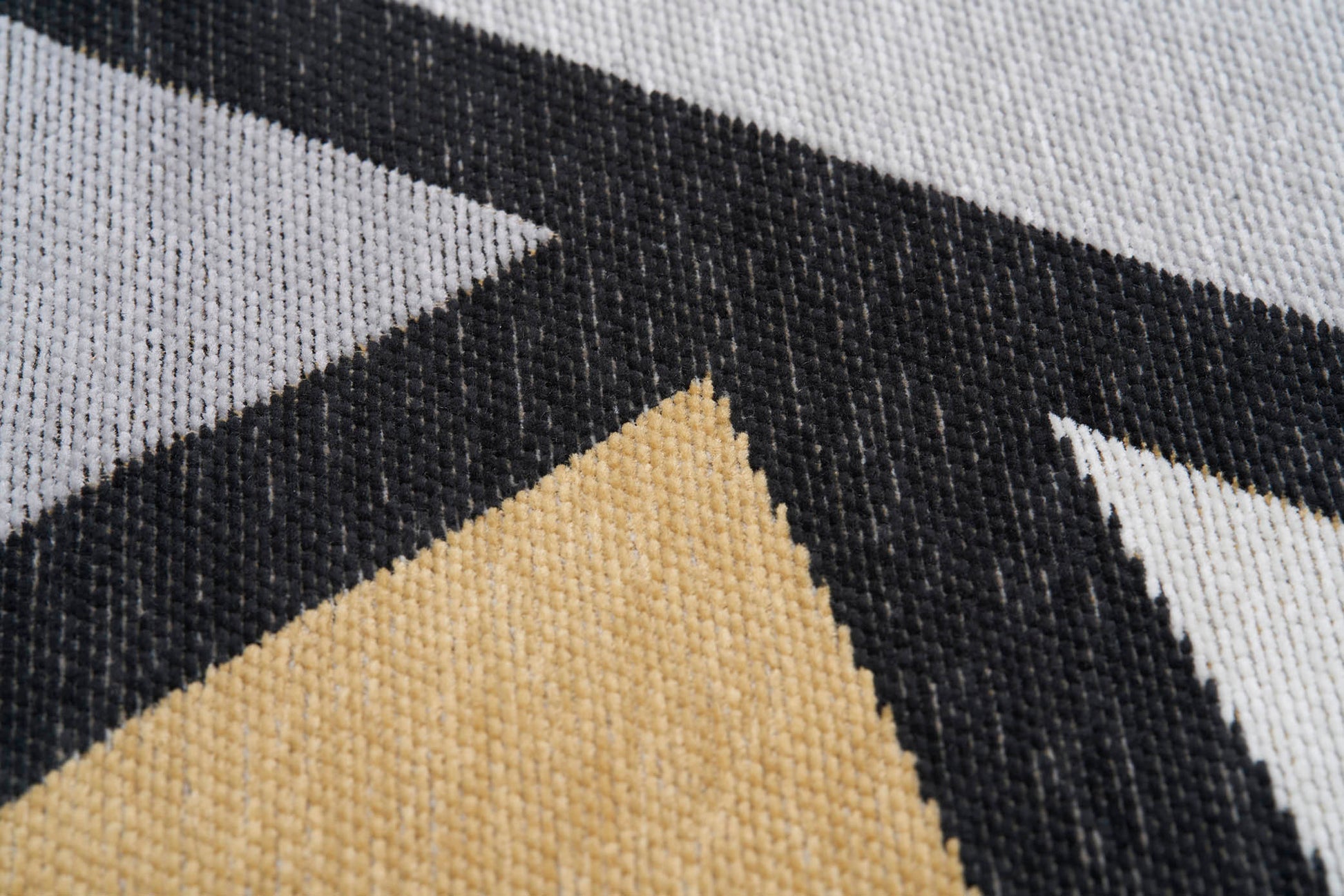 Gros plan sur un tapis lavable Freya à motifs géométriques jaune, gris et noir, révélant la texture et les fibres.