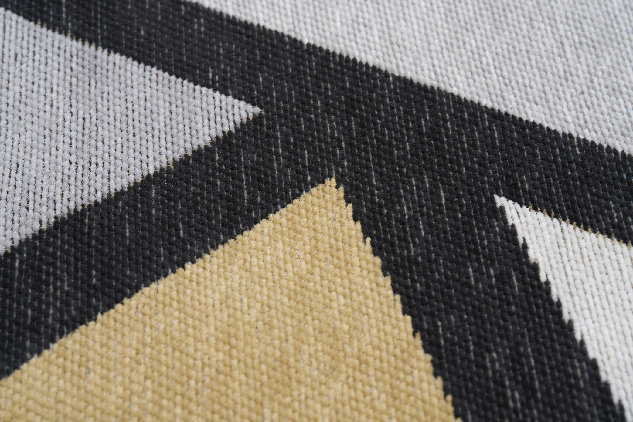 Gros plan sur un tapis lavable Freya à motifs géométriques jaune, gris et noir, révélant la texture et les fibres.