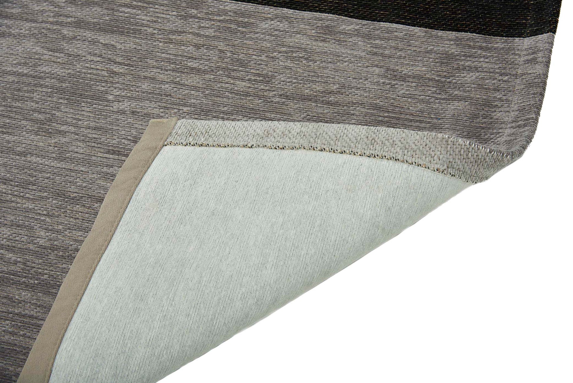 Gros plan sur un tapis moderne aux rayures beiges, grises et noires, révélant la texture des fibres, avec son revers en coton clair.