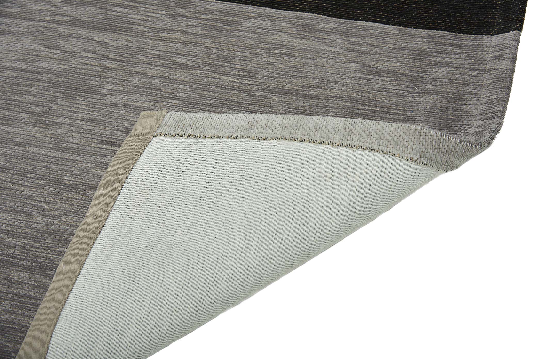 Gros plan sur un tapis moderne aux rayures beiges, grises et noires, révélant la texture des fibres, avec son revers en coton clair.