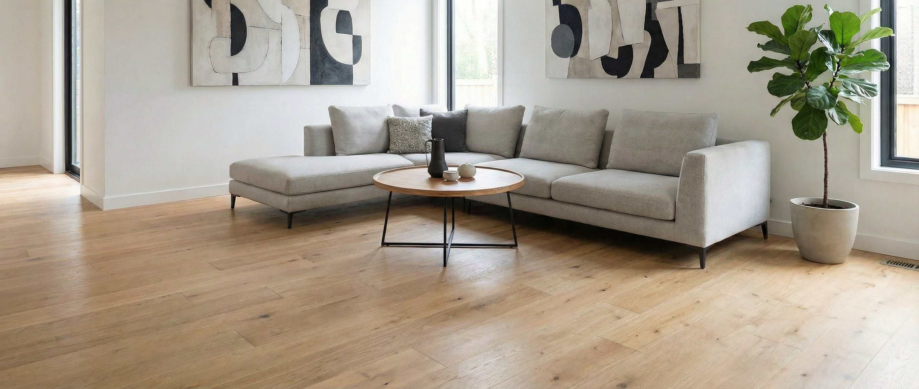 Pièce lumineuse avec plancher en bois clair. Canapé gris, tables basses rondes. Espace vide pour un tapis rectangulaire