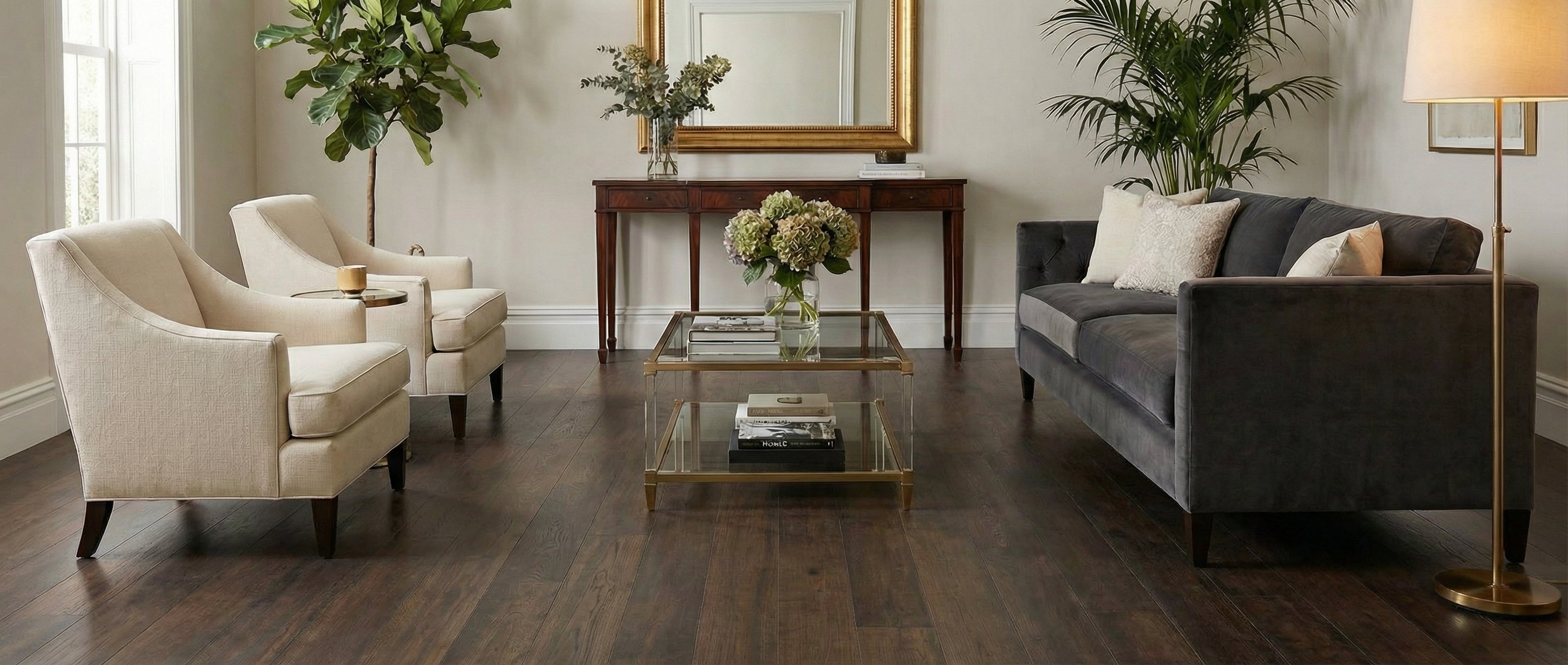 Pièce lumineuse, parquet foncé, canapé gris, fauteuils beiges. Espace vide pour un tapis rectangulaire, ambiance chaleureuse