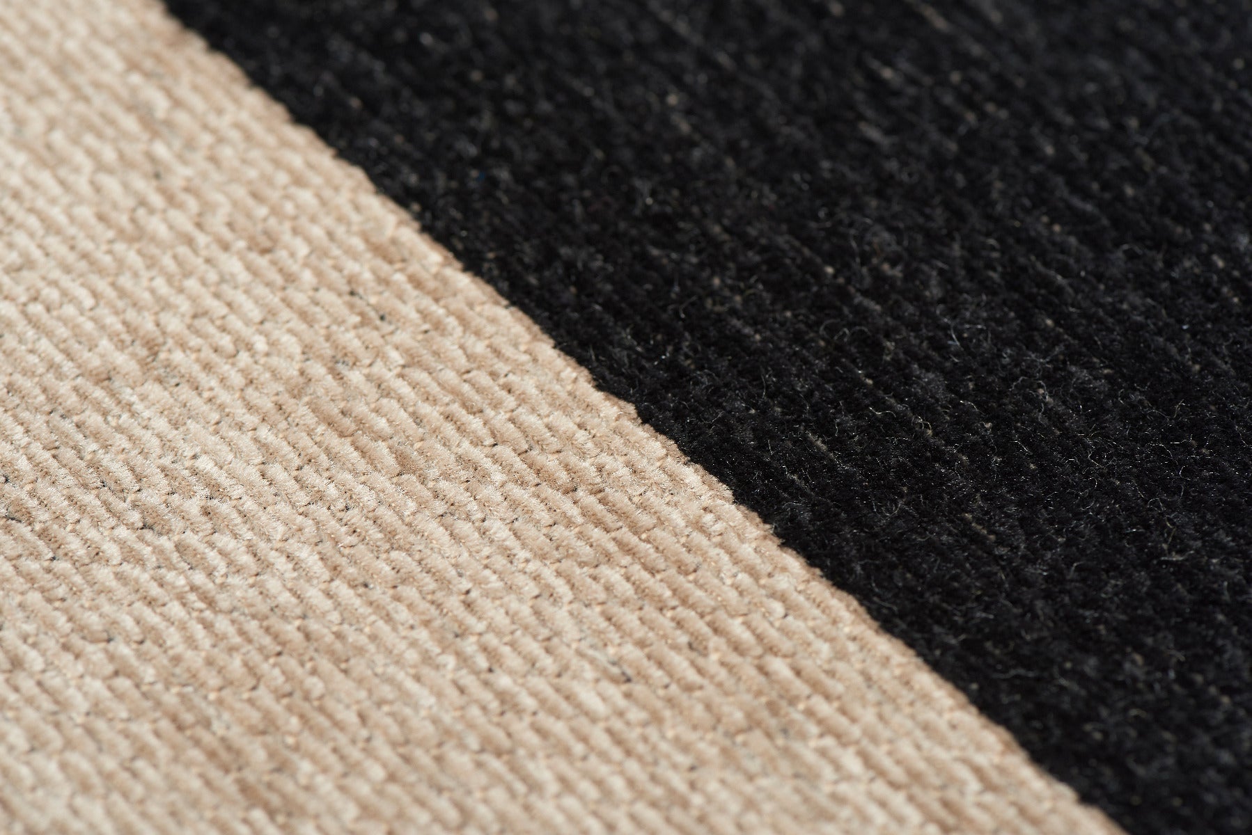 Tapis rayé noir et beige. Tissage texturé avec relief. Aspect tactile et doux. Rectangulaire
