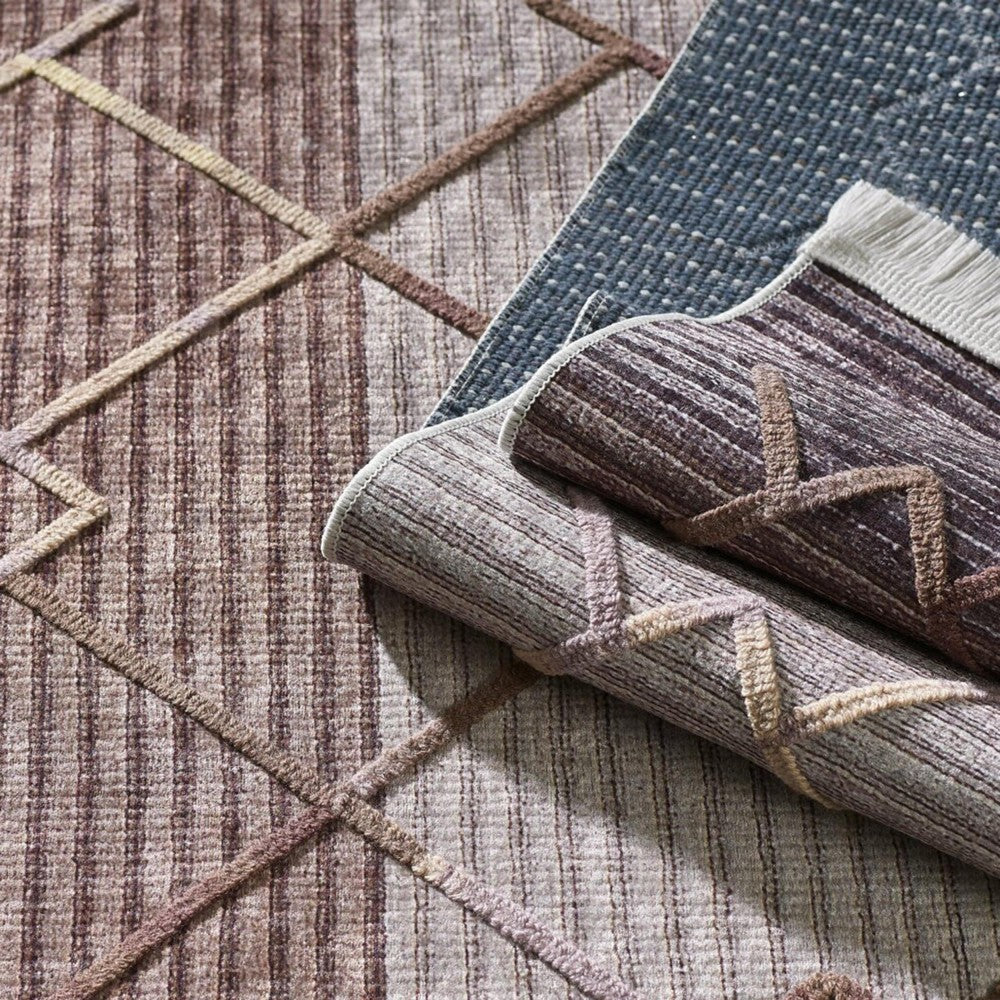 Divers tapis textiles aux motifs variés : un tapis plat brun-beige à rayures et quadrillage, des tapis enroulés à motifs géométriques en relief et un tapis bleu à pois