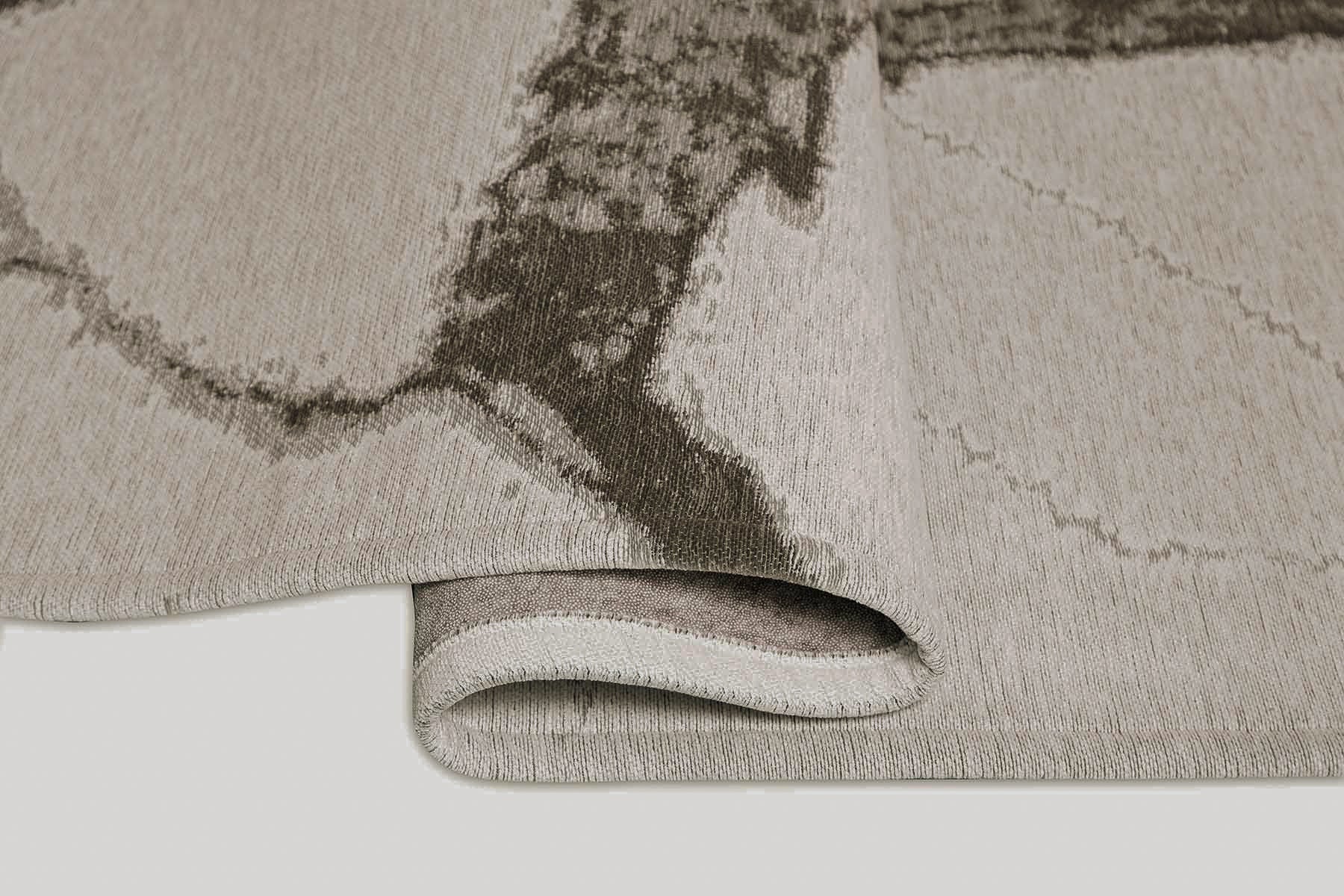 Vue rapprochée d'un tapis lavable moderne gris enroulé, révélant une épaisseur texturée et un design contemporain.