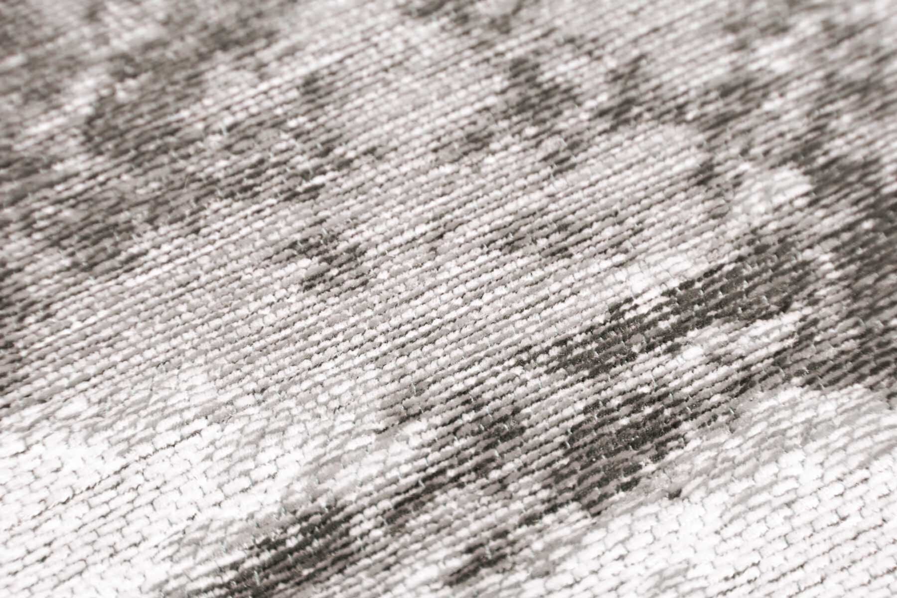 Gros plan sur un tapis lavable moderne Ivoire, révélant une texture épaisse et un design texturé en tons de gris et blanc.