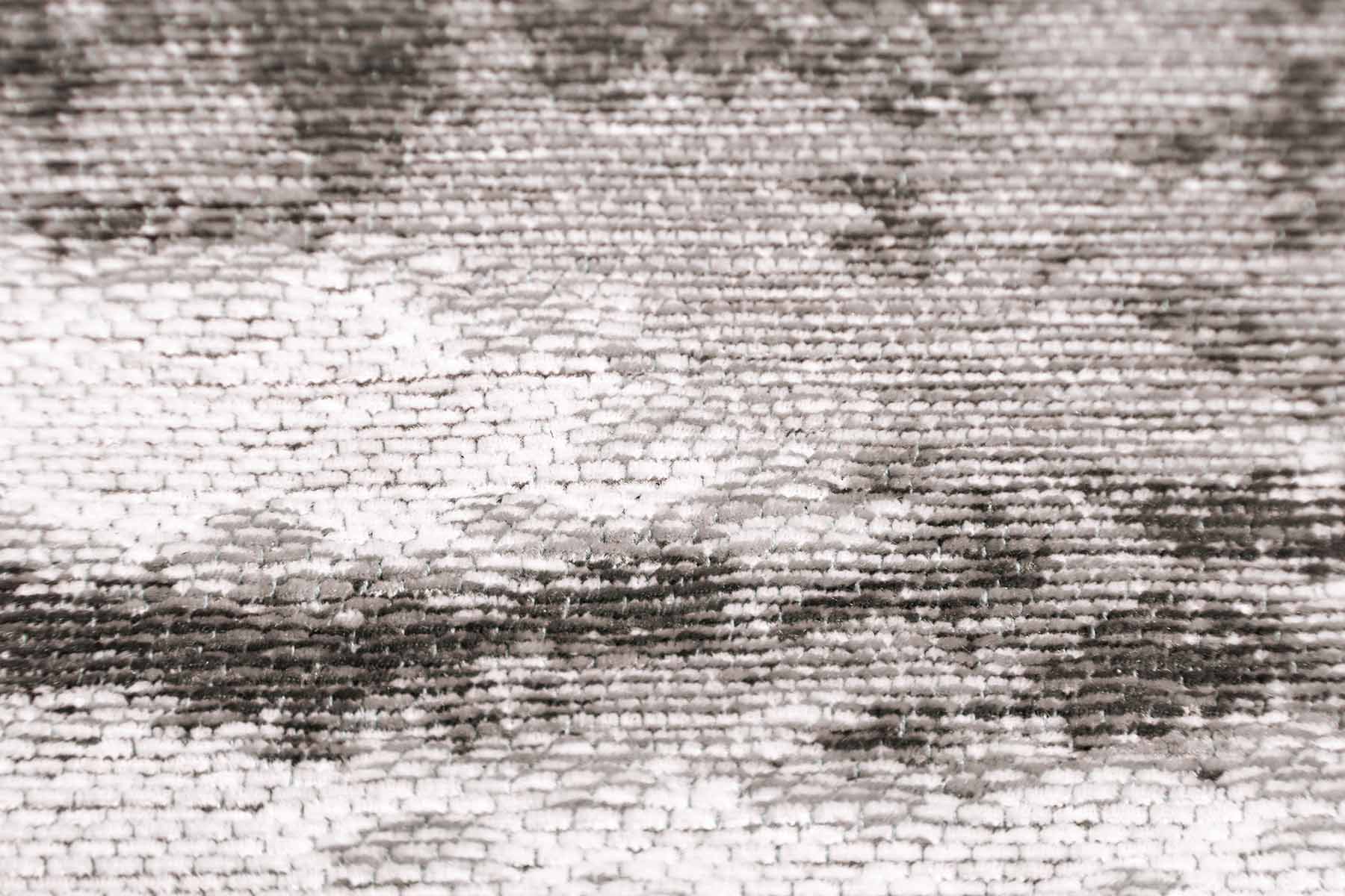 Gros plan sur un tapis lavable moderne Ivoire, révélant une texture épaisse et un design texturé en tons de gris et blanc.