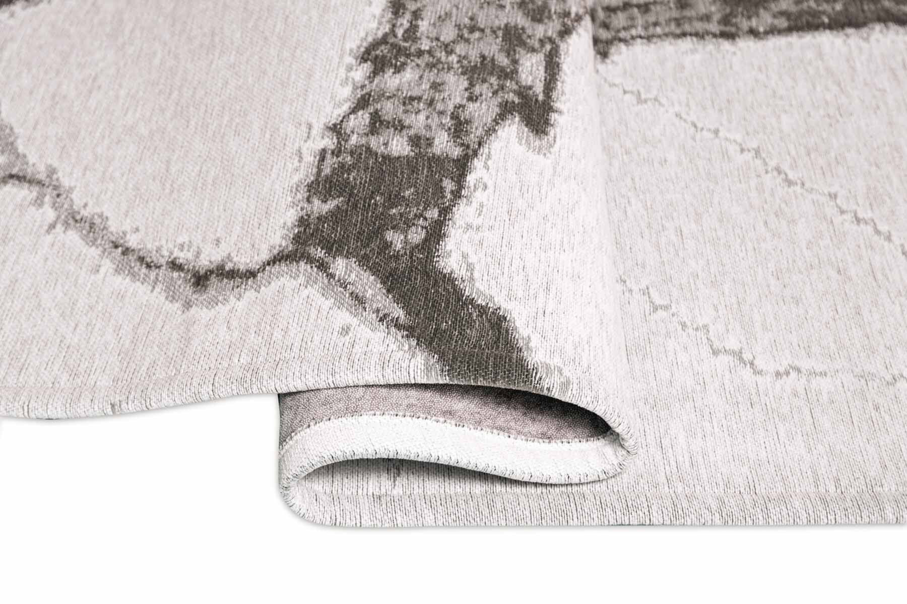 Vue en gros plan d'un tapis moderne ivoire avec des motifs gris, révélant son épaisseur et sa texture.