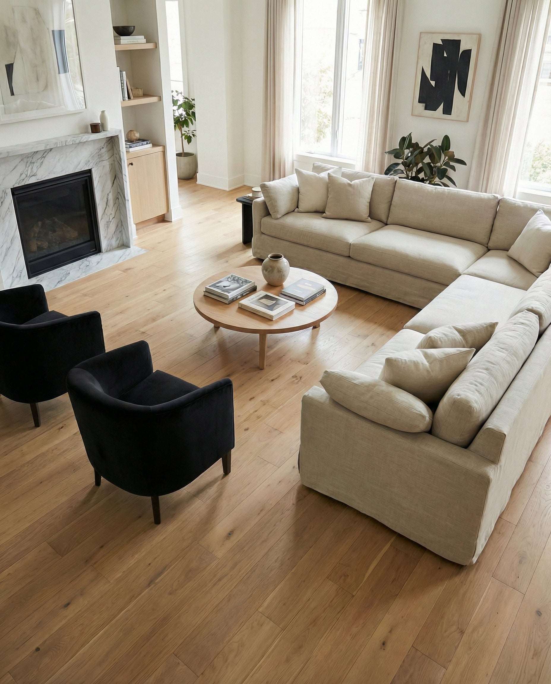 Pièce lumineuse avec canapé beige, fauteuils noirs, cheminée et parquet clair. Espace à transformer