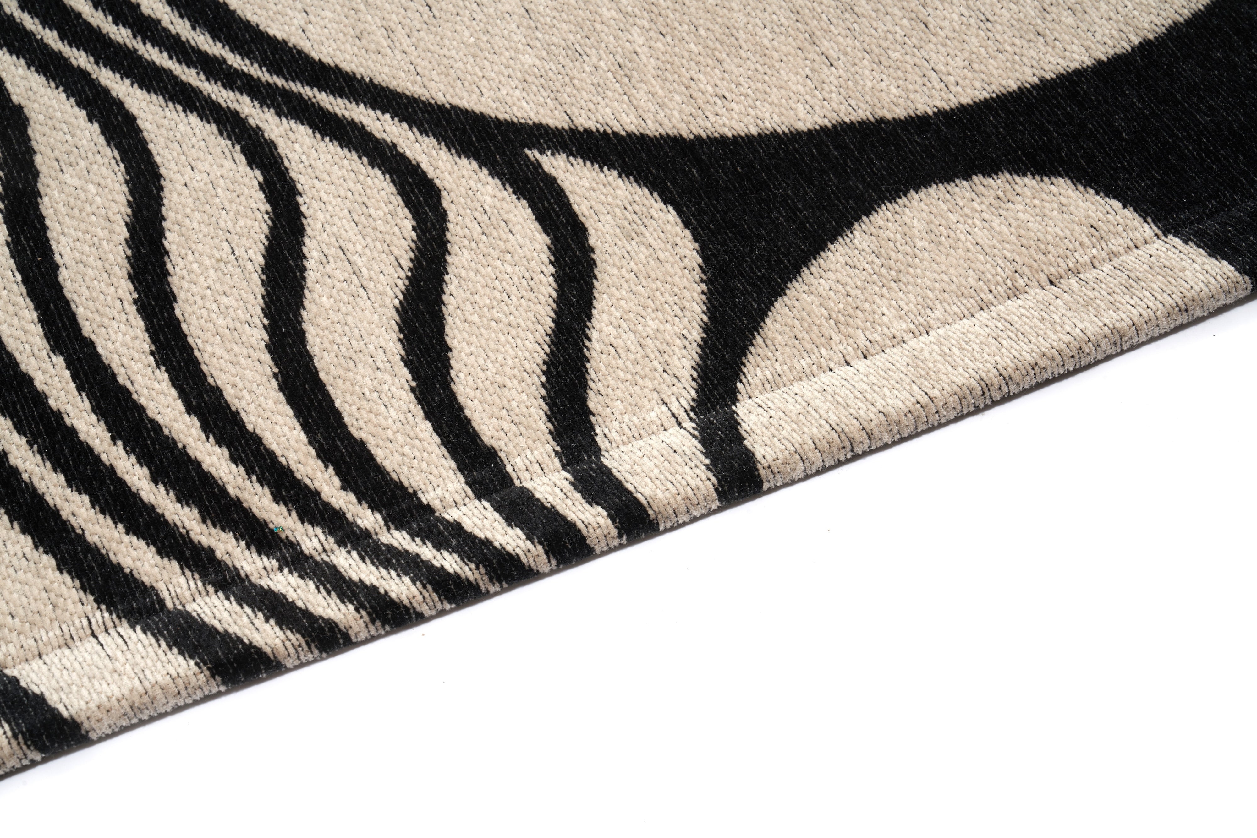 Tapis rectangulaire en laine, tissage dense. Motif abstrait noir et beige. Relief tactile, lignes courbes. Ambiance
