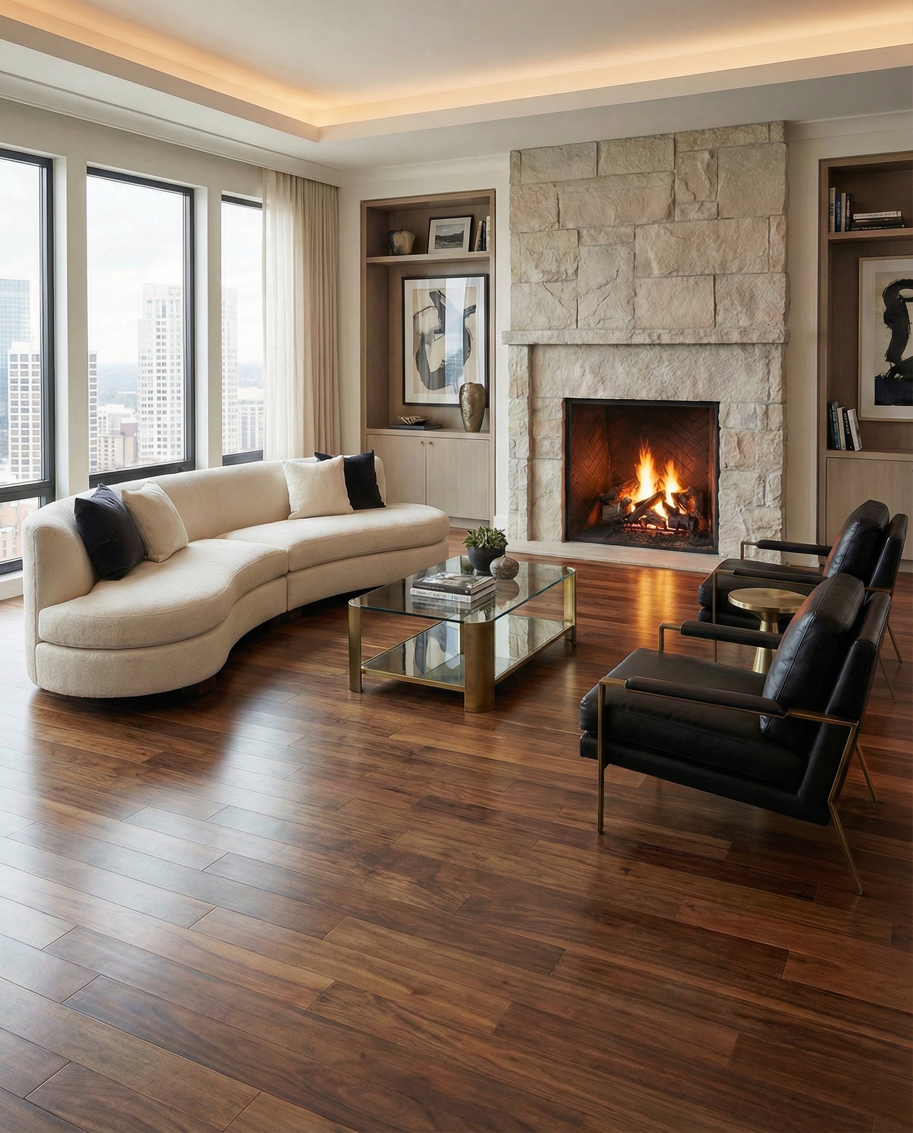 Pièce avec plancher bois foncé, canapé clair incurvé, fauteuils noirs, cheminée en pierre, ambiance chaleureuse