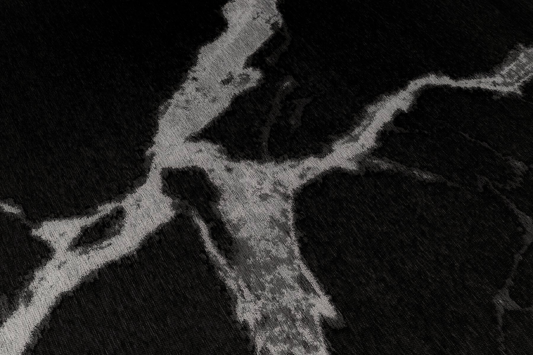 Tapis noir et blanc, tissage texturé avec relief. Aspect tactile évoquant une peau animale, ambiance feutrée