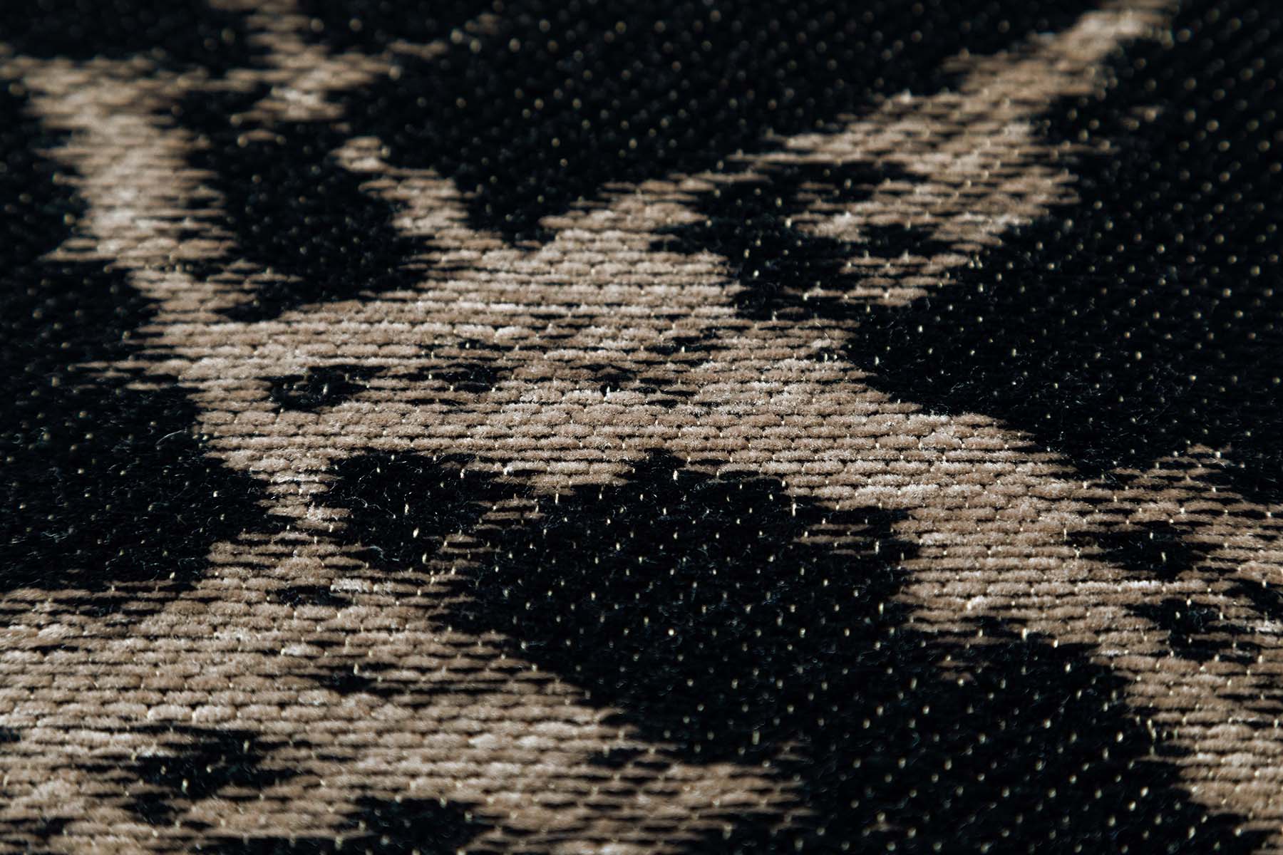 Tapis à motif léopard, tissage serré, relief subtil, aspect tactile velouté, couleurs noir et beige, ambiance feutrée