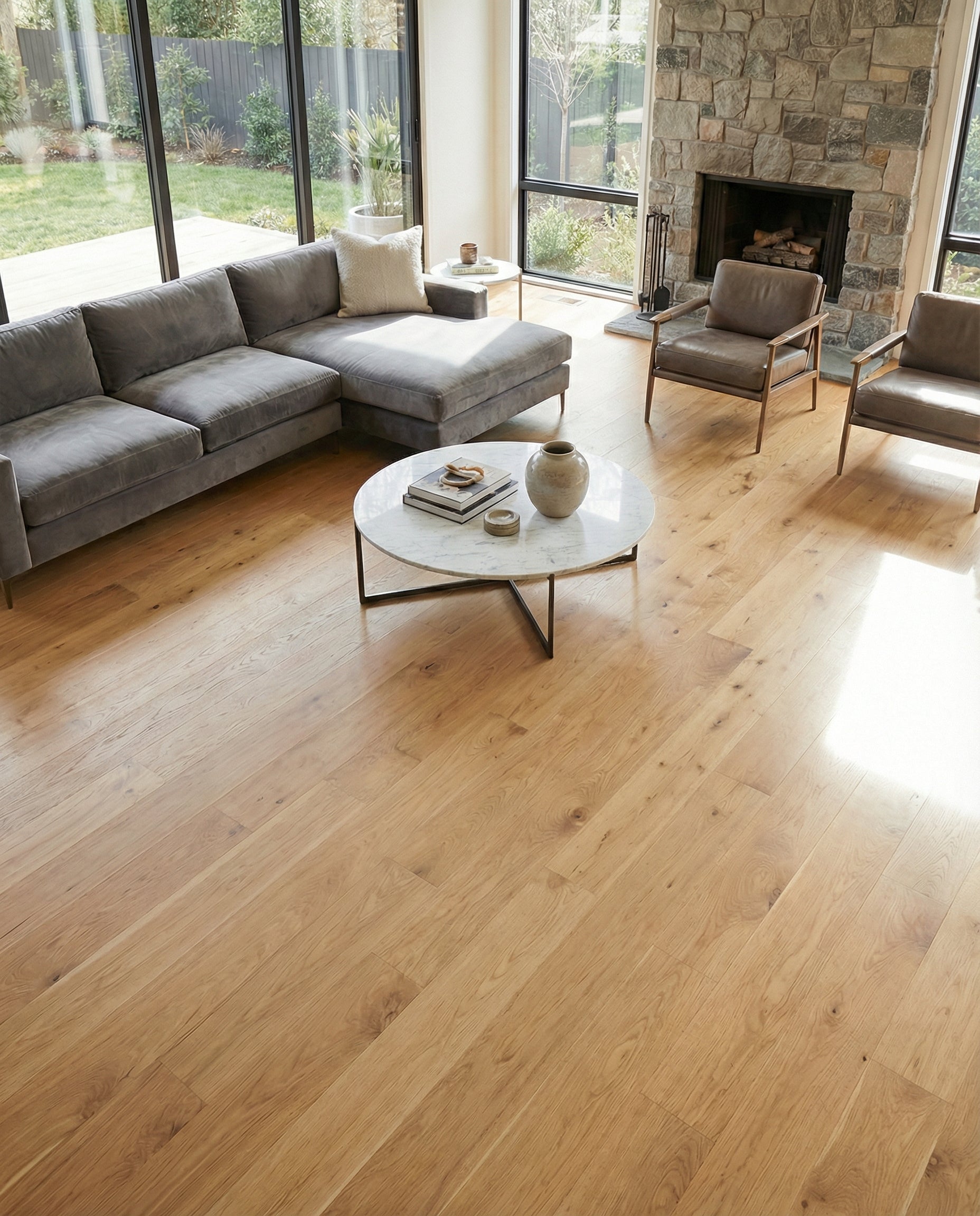 Pièce lumineuse avec parquet, canapé incurvé, fauteuils et table basse rectangulaire noire. Ambiance chaleureuse