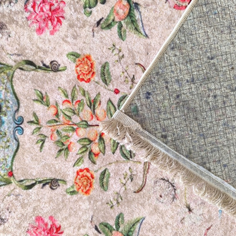 Tapis velouté beige à motifs floraux roses, oranges et verts, son revers quadrillé antidérapant et ses franges