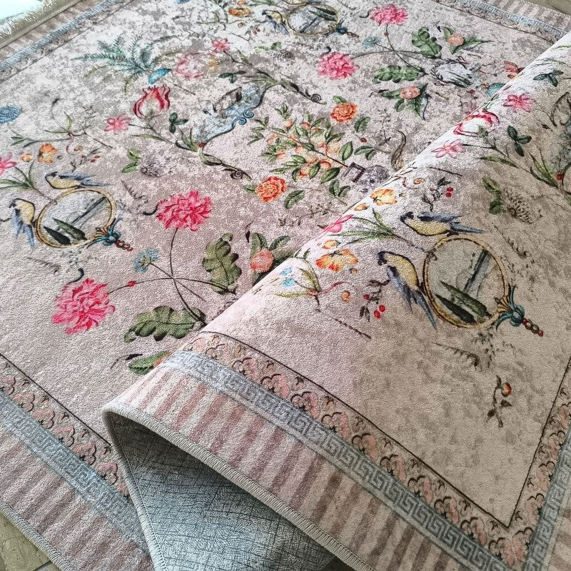 Tapis beige doux et texturé orné de motifs floraux vifs de roses roses et oranges, de feuilles vertes et d'oiseaux bleus avec une bordure élégante présentant des rayures et un motif grec