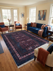 Tapis rectangulaire bleu nuit avec motifs géométriques bordeaux et crème, franges, sur parquet d'un salon