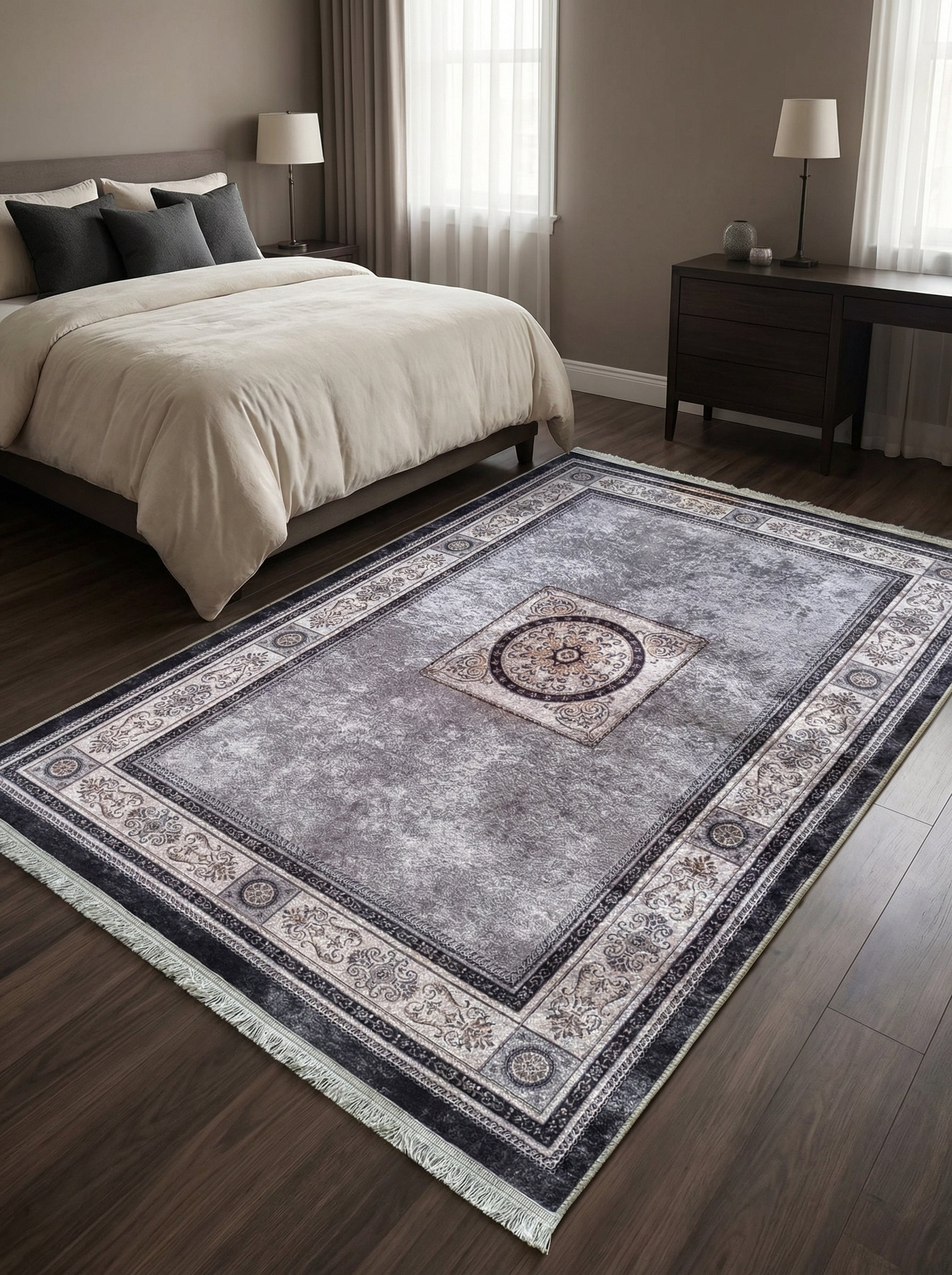 Tapis rectangulaire gris chiné à motifs classiques noirs et beiges, médaillon central, franges, posé dans une chambre