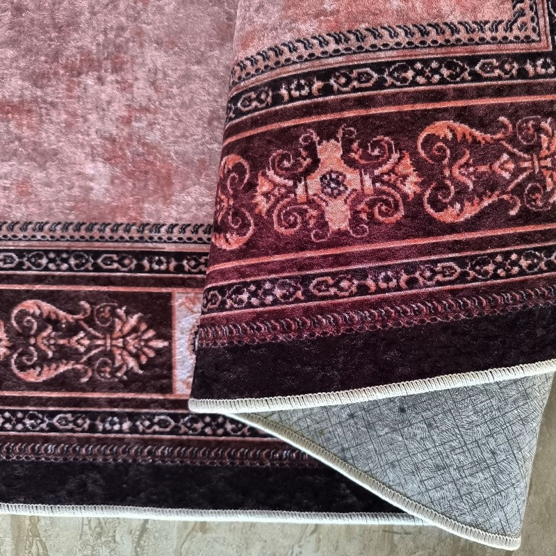 Tapis aux motifs orientaux bordeaux et rose, avec un velours doux et un envers gris antidérapant partiellement visible