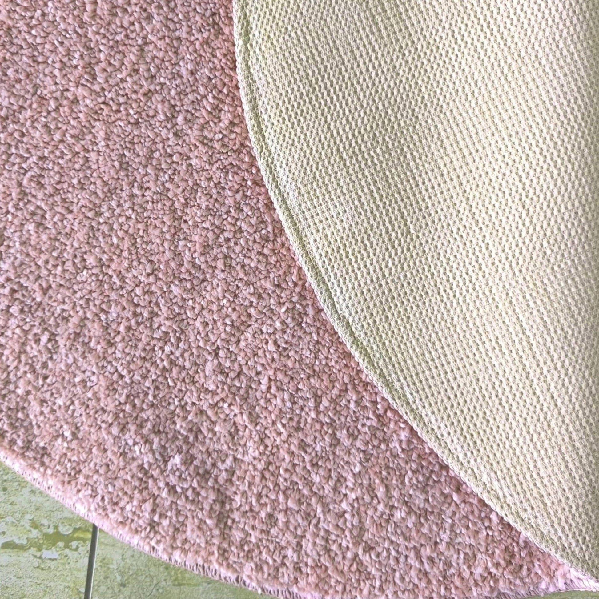 Tapis rose poudré à la texture douce et duveteuse, avec son revers quadrillé vert pâle visible