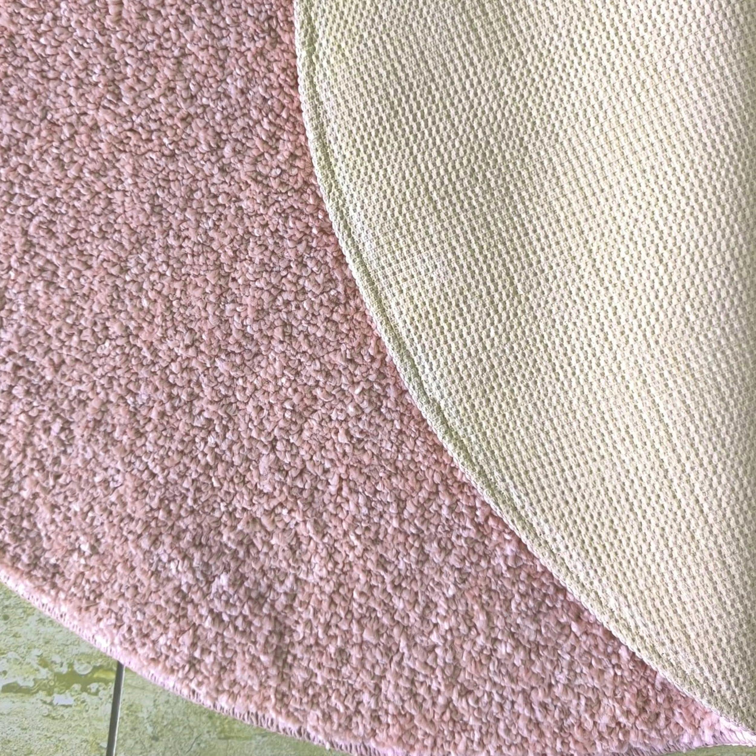 Tapis rose poudré à la texture douce et duveteuse, avec son revers quadrillé vert pâle visible