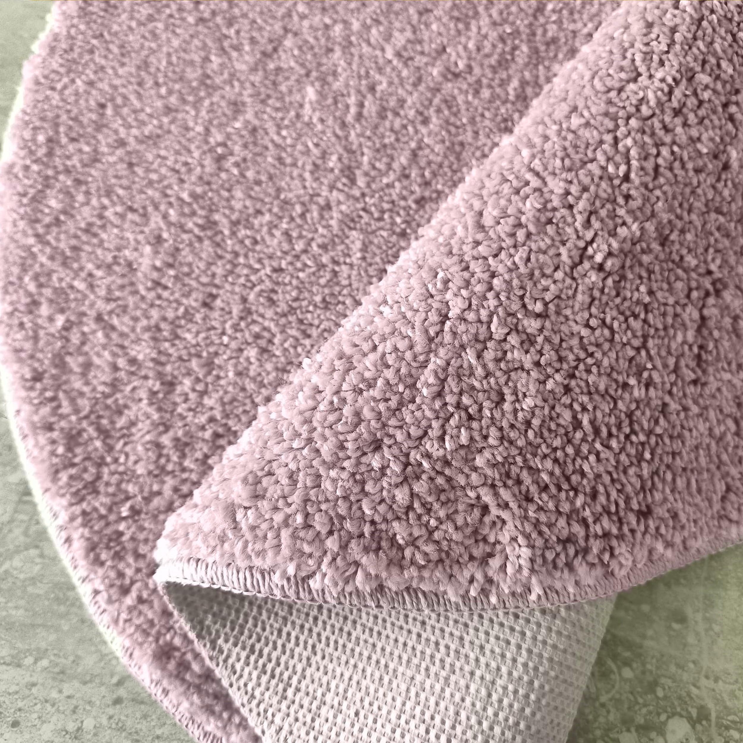 Tapis rose poudré à poil long et bouclé, replié sur son envers gaufré gris clair et un sol marbré vert pâle