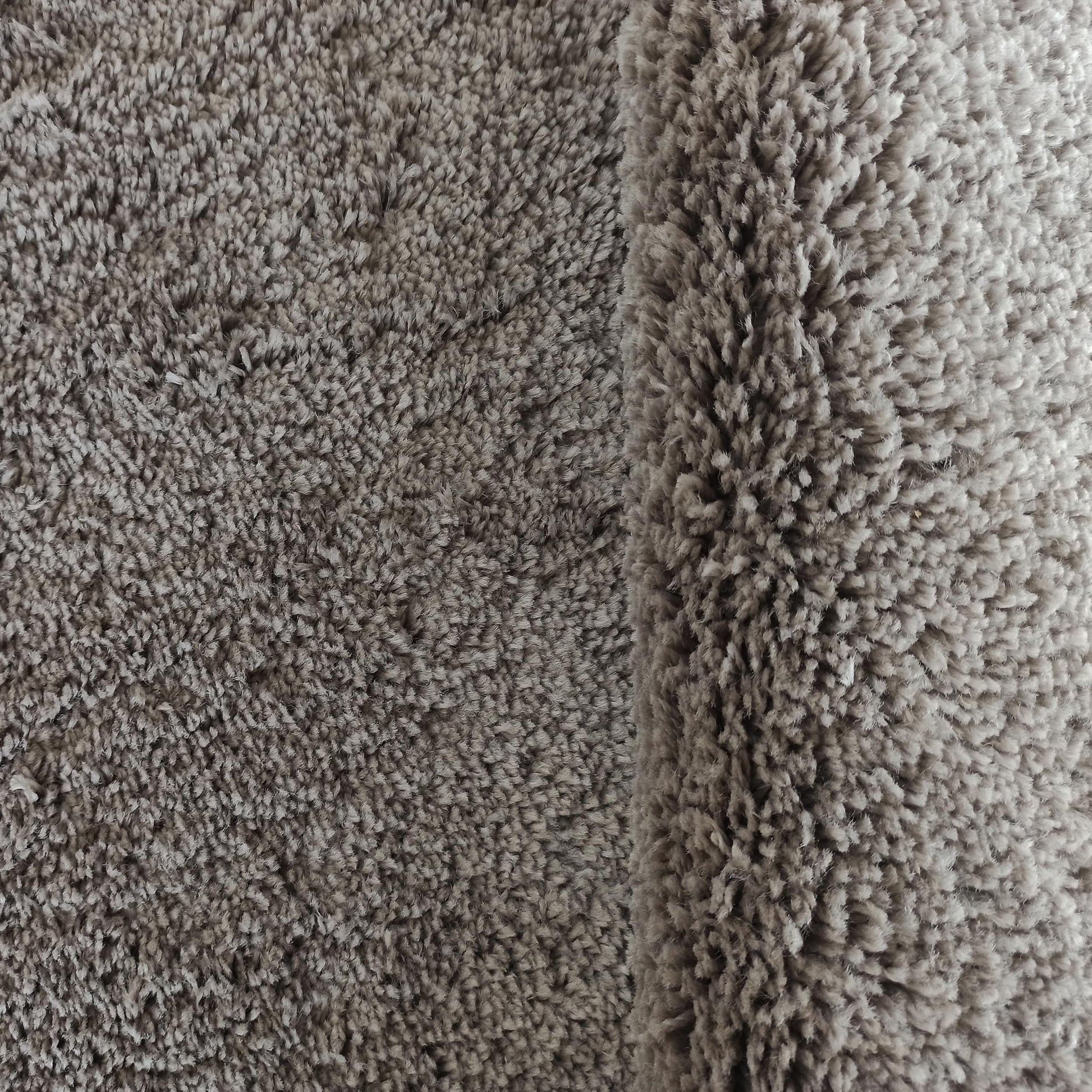 Tapis moelleux à poils longs de couleur taupe, présentant une texture douce et un pli sur le côté droit