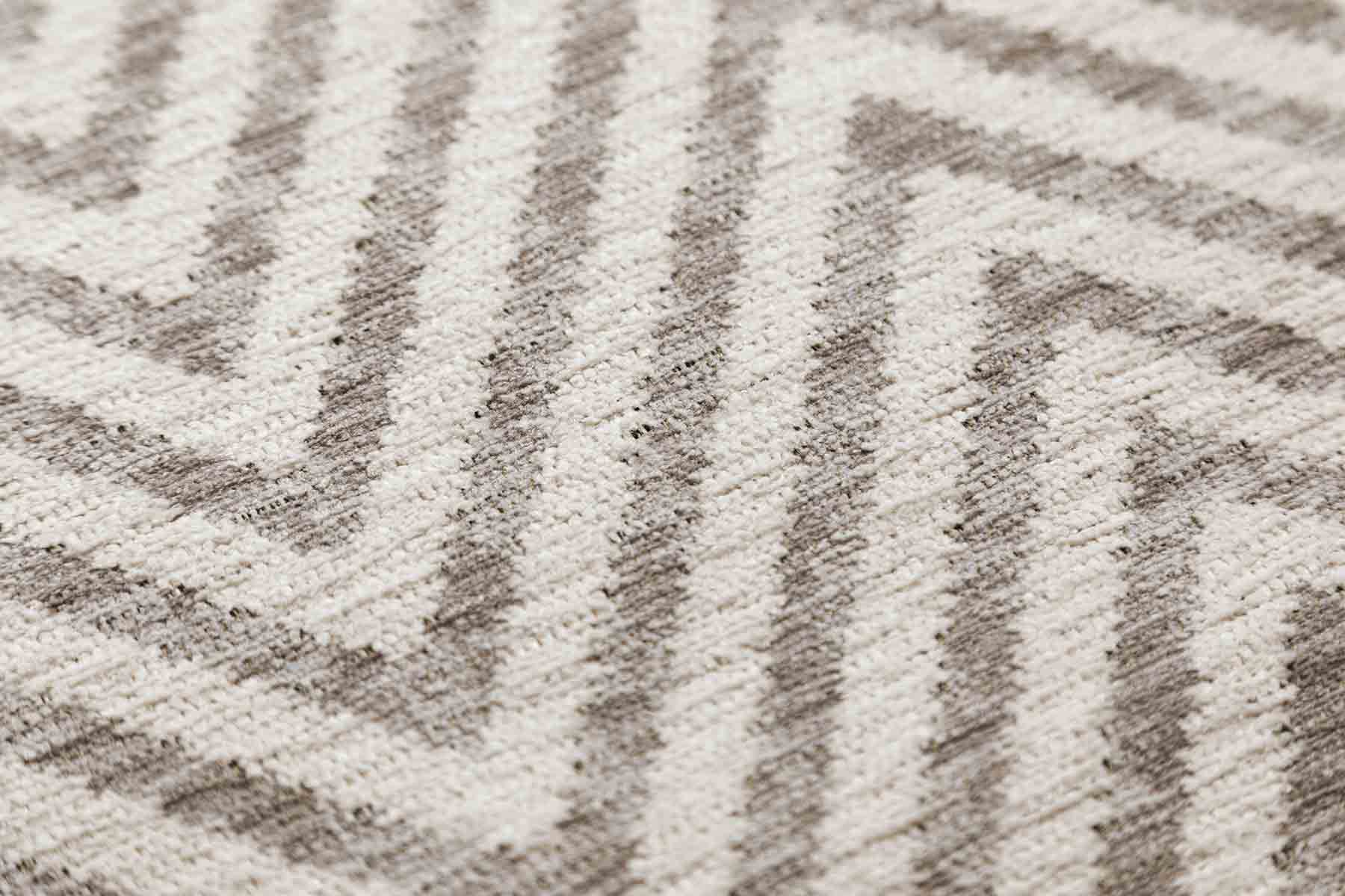 Gros plan sur la texture d'un tapis scandinave lavable beige : on distingue des fibres tissées formant des motifs géométriques en zigzag.