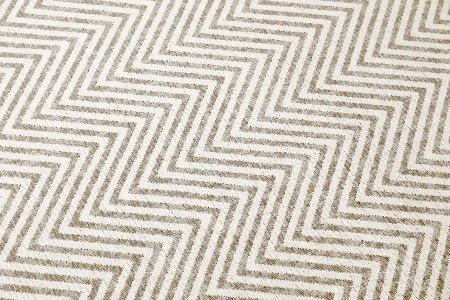 Zoom sur un tapis lavable de style scandinave, avec un motif chevron beige et blanc offrant une texture fibreuse.