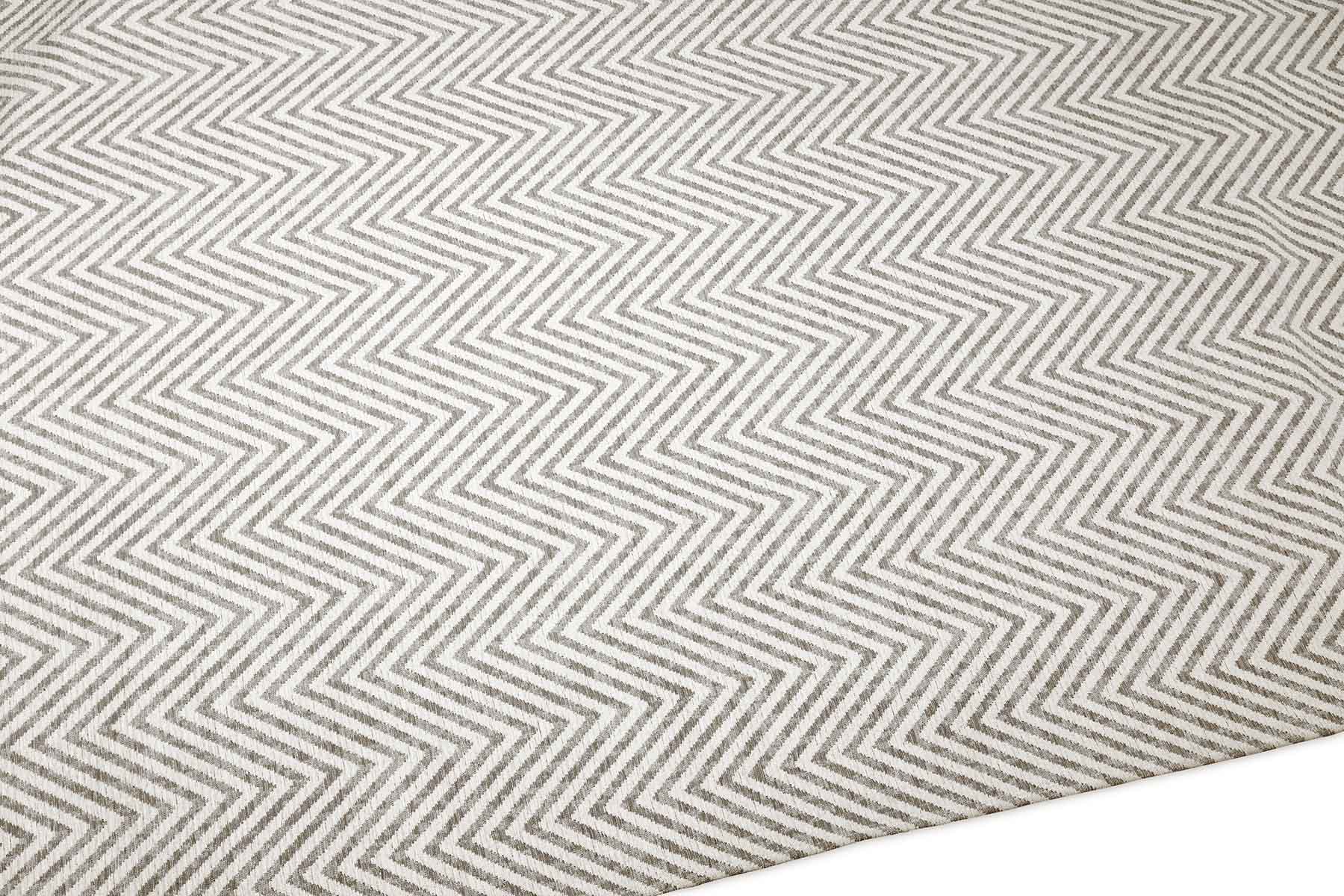 Tapis à chevrons beige et blanc, tissage plat. Motif en zigzag, relief léger. Aspect tactile texturé