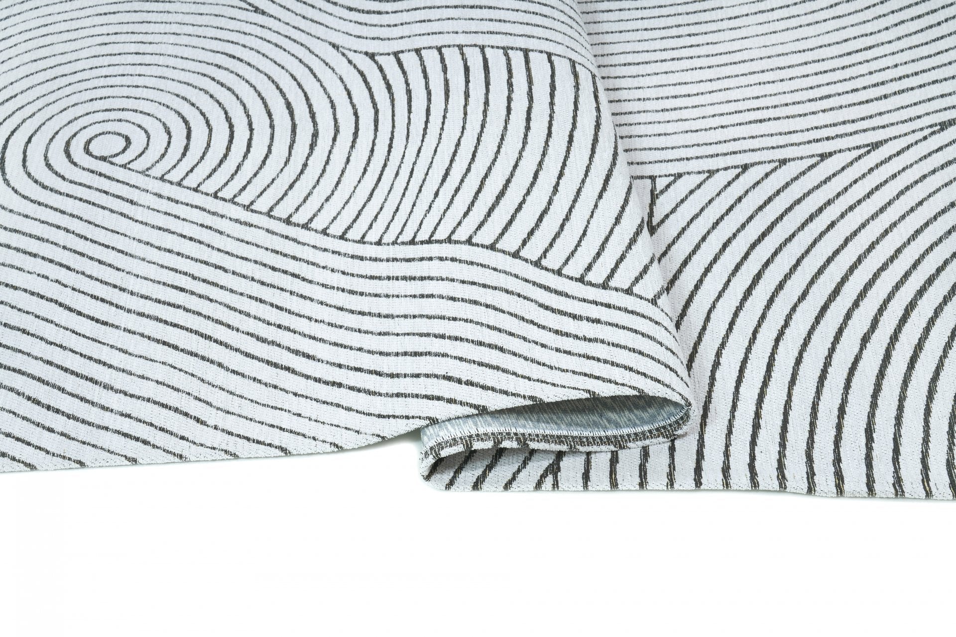 Tapis rectangulaire blanc et noir. Motif linéaire et en spirale. Apparence dense et confortable