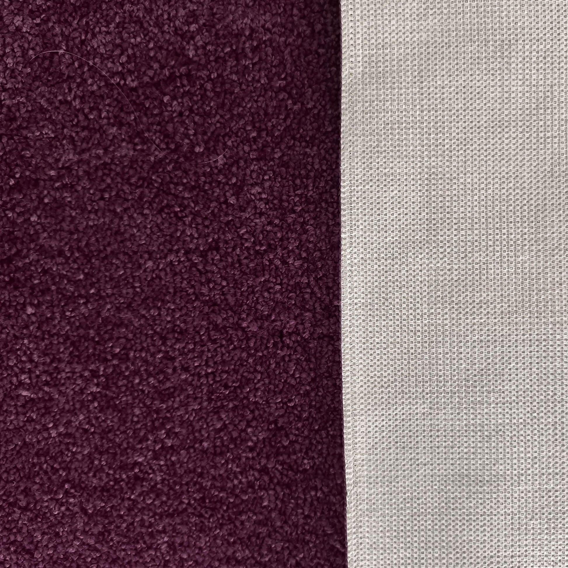 Gros plan sur un tapis violet foncé à la texture épaisse et son envers gris clair présentant un motif quadrillé