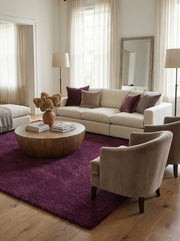 Grand tapis shaggy violet foncé au centre d'un salon élégant, agrémenté d'un canapé clair et de fauteuils taupe