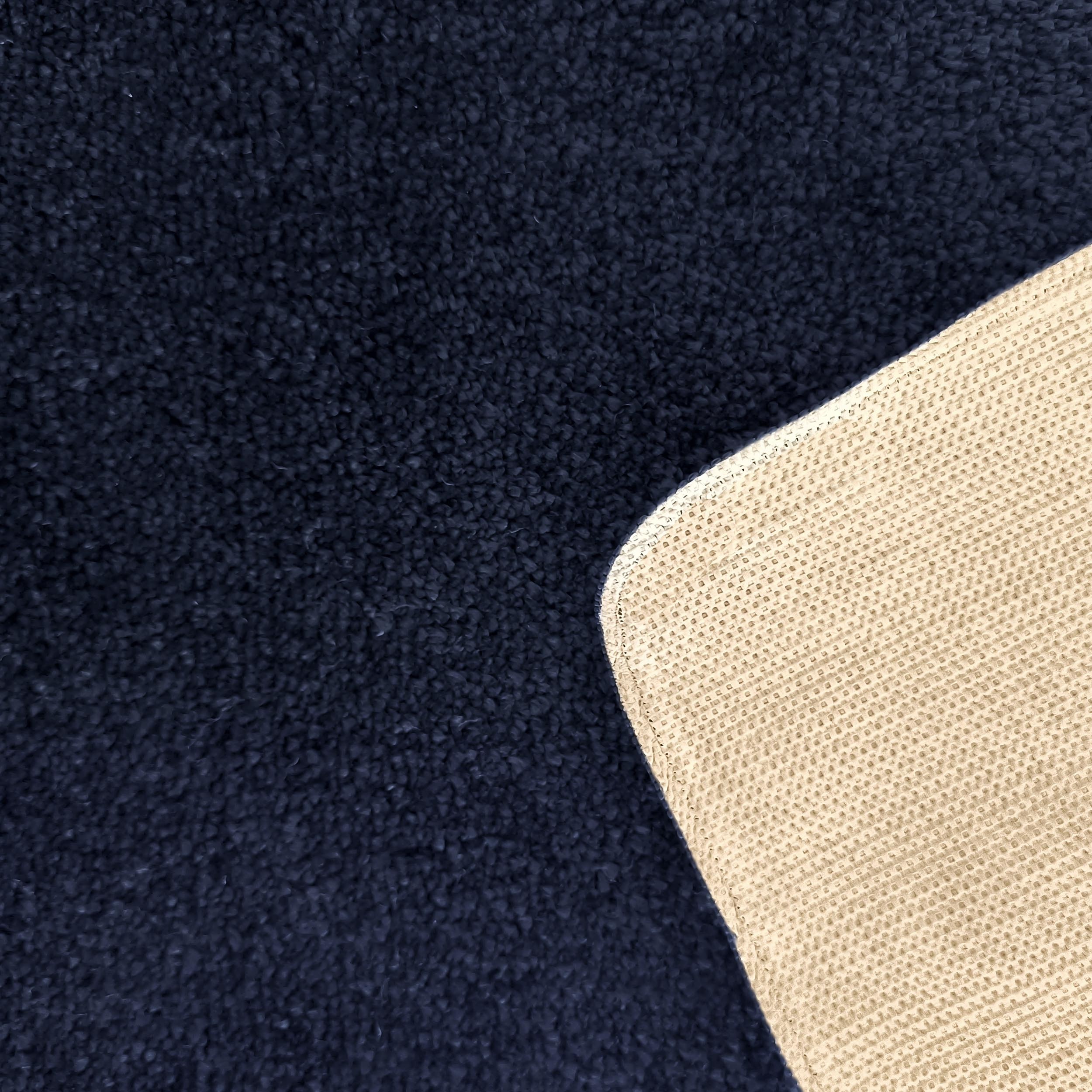Tapis bleu marine à texture bouclée et son envers en tissu beige clair avec motif quadrillé
