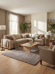 Tapis rectangulaire gris-taupe à poils longs et moelleux, posé sur un parquet clair dans un salon