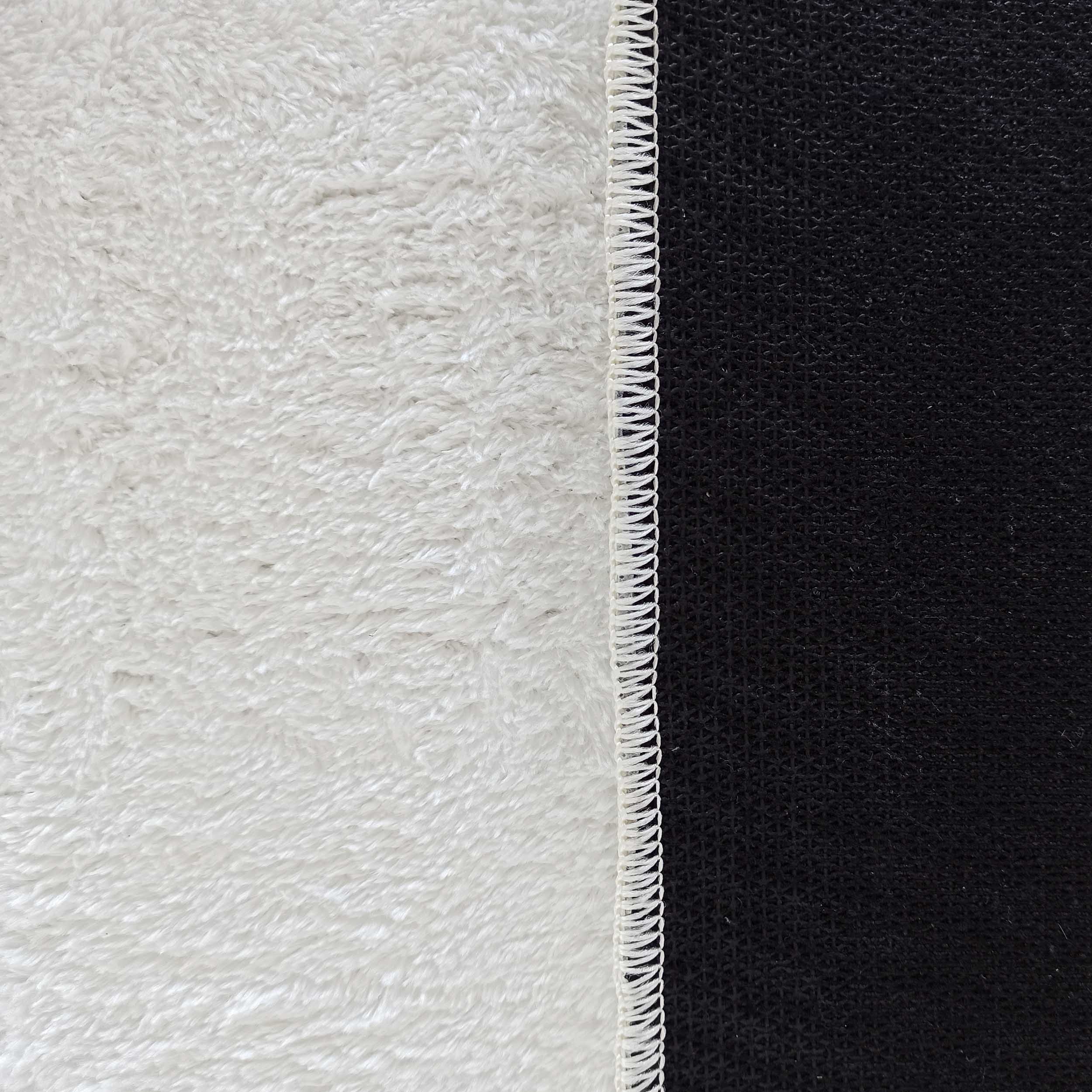 Tapis blanc à la texture dense et moelleuse, bordure blanche cousue et envers noir texturé quadrillé