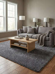Tapis rectangulaire gris foncé à poils longs posé sur un parquet en bois dans un salon lumineux
