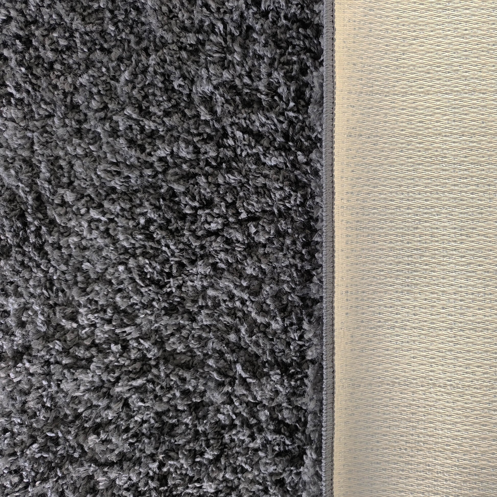 Tapis gris à poils longs et bouclés, avec une bande de finition grise et un revers beige clair texturé de motifs en losanges