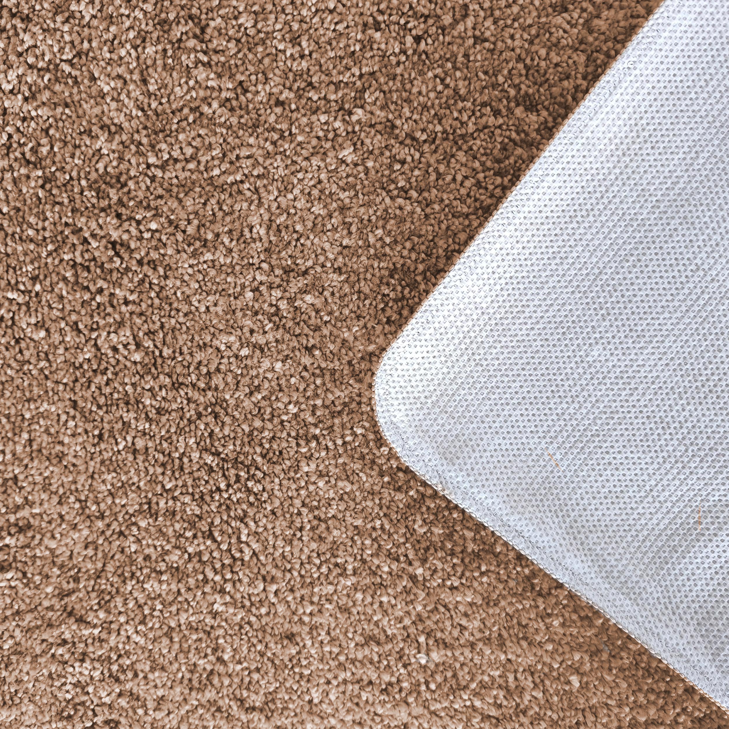 Tapis doux marron clair à texture bouclée, montrant son envers gris clair à motif de petits points