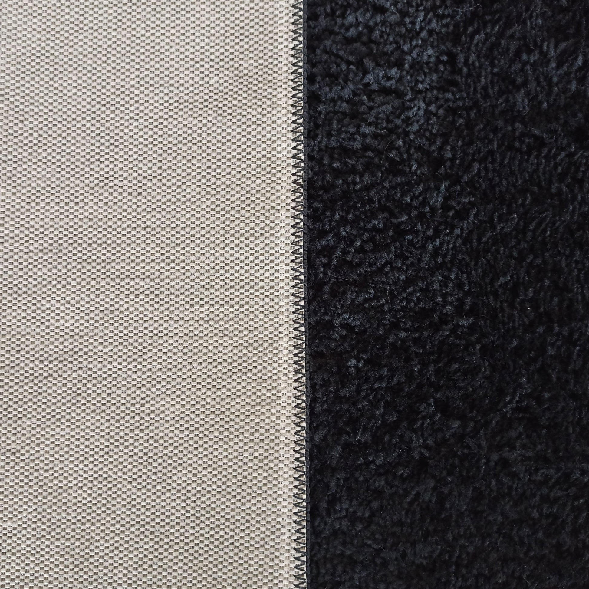 Tapis bicolore : un côté en tissage beige clair quadrillé et l'autre noir à poils longs et épais, avec une couture noire centrale