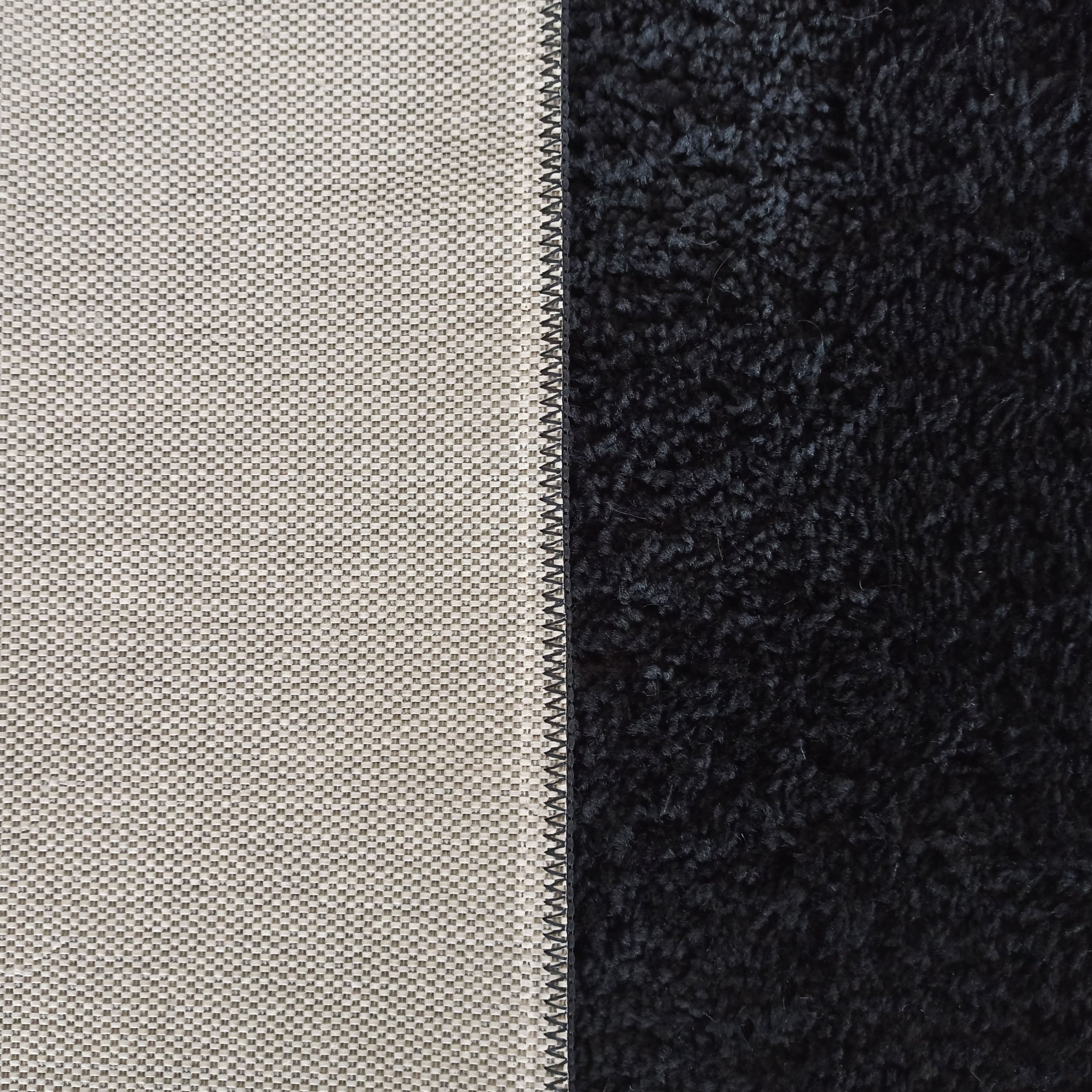 Tapis bicolore : un côté en tissage beige clair quadrillé et l'autre noir à poils longs et épais, avec une couture noire centrale
