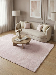 Tapis rectangulaire rose pâle à poils longs et doux, posé sur un parquet clair dans un salon moderne aux tons neutres