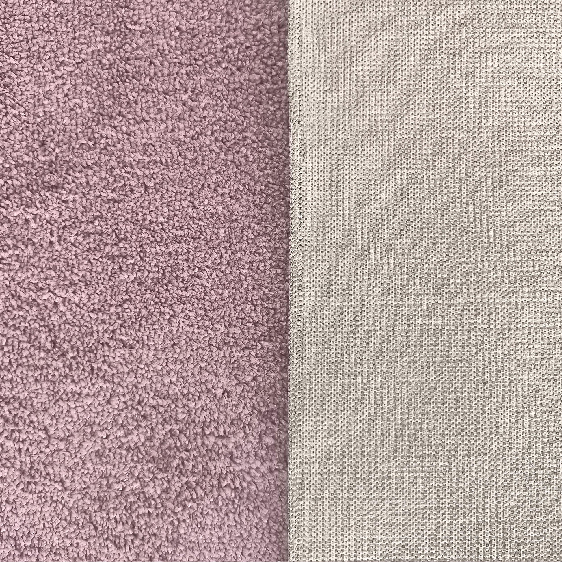 Un tapis rose mauve à la texture bouclée et douce, dont le revers est beige clair avec un motif de petits carrés antidérapants
