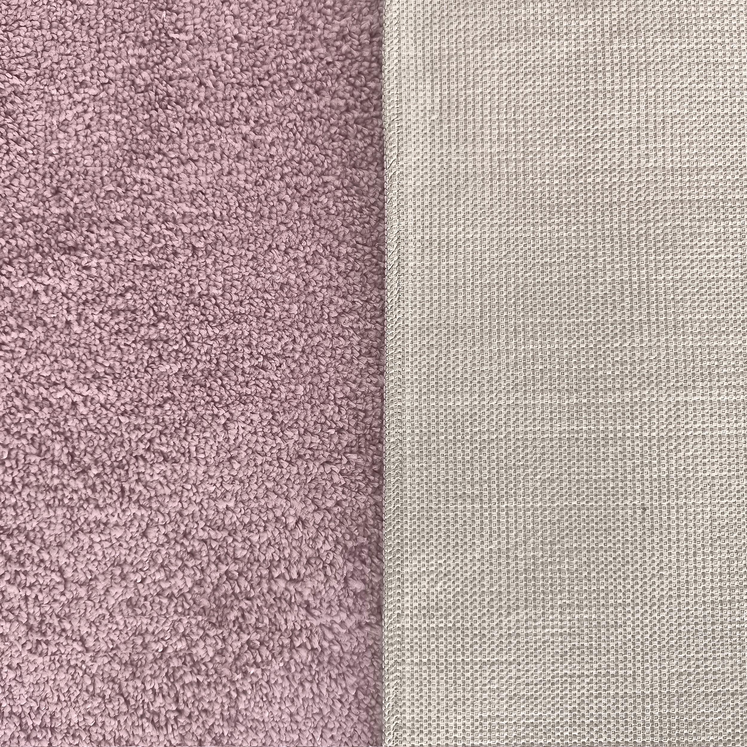 Un tapis rose mauve à la texture bouclée et douce, dont le revers est beige clair avec un motif de petits carrés antidérapants