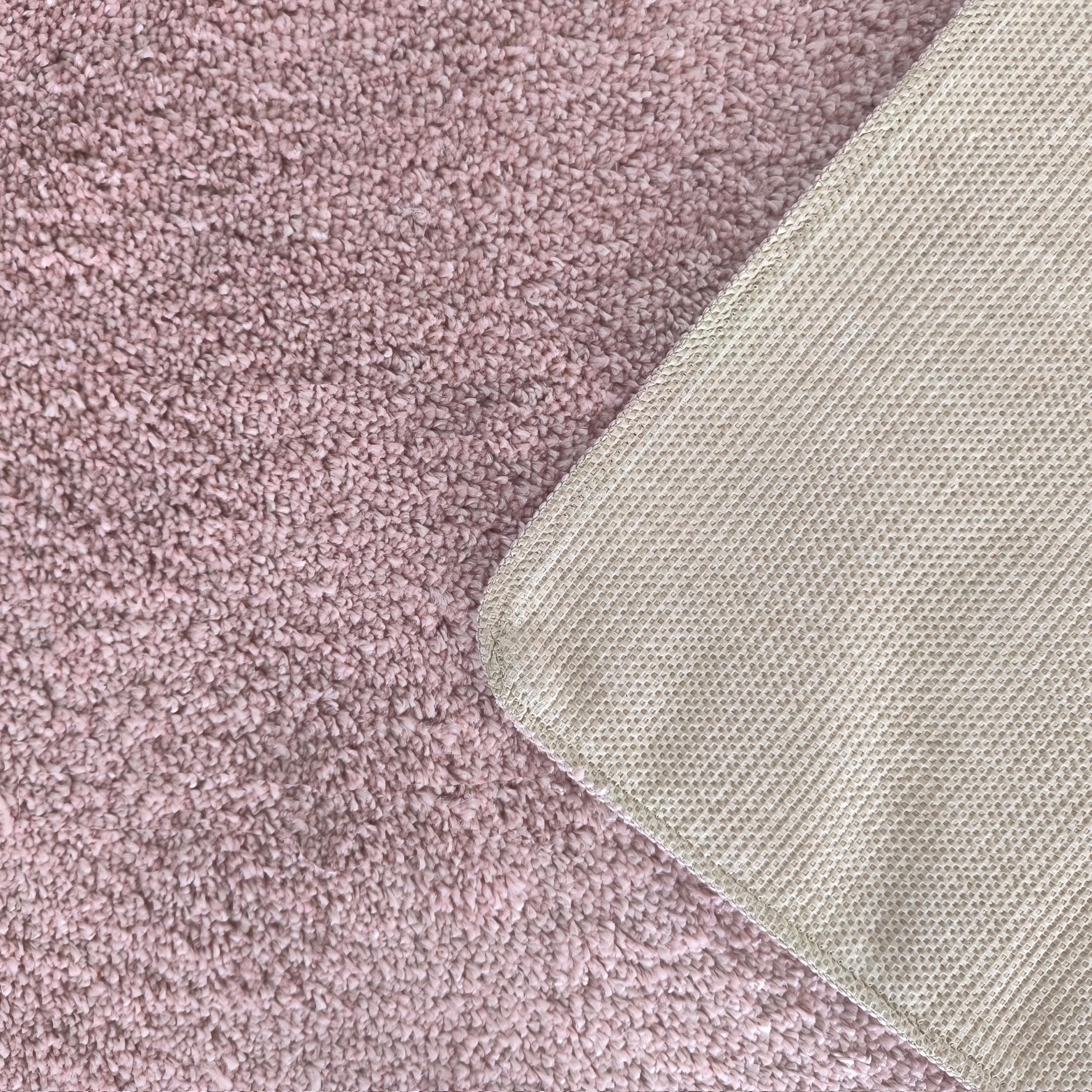 Tapis rose mauve à poils longs et revers antidérapant beige clair à motif quadrillé, montrant les deux côtés