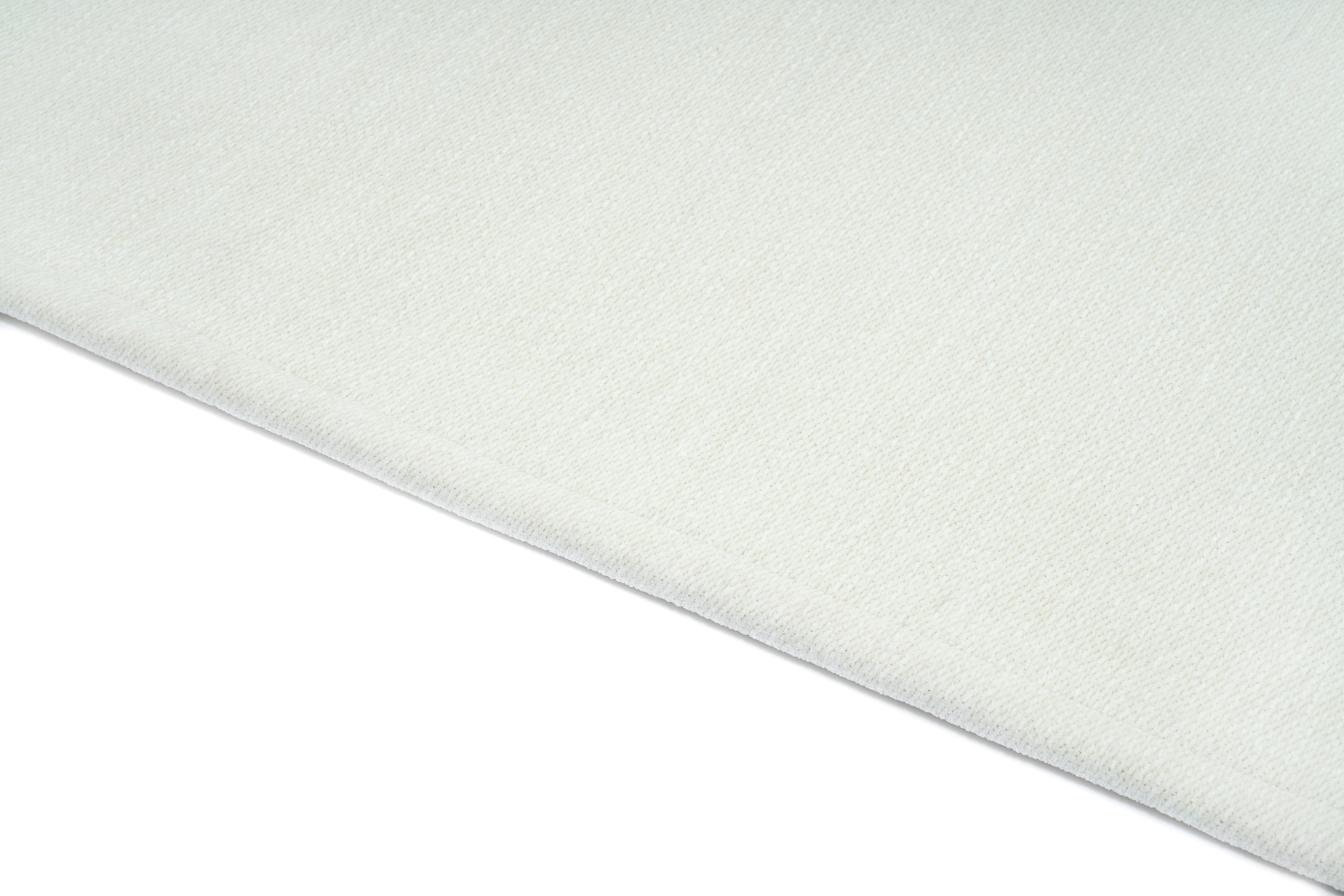 Tapis blanc, tissage texturé, relief subtil, aspect tactile doux. Ambiance sobre et épurée