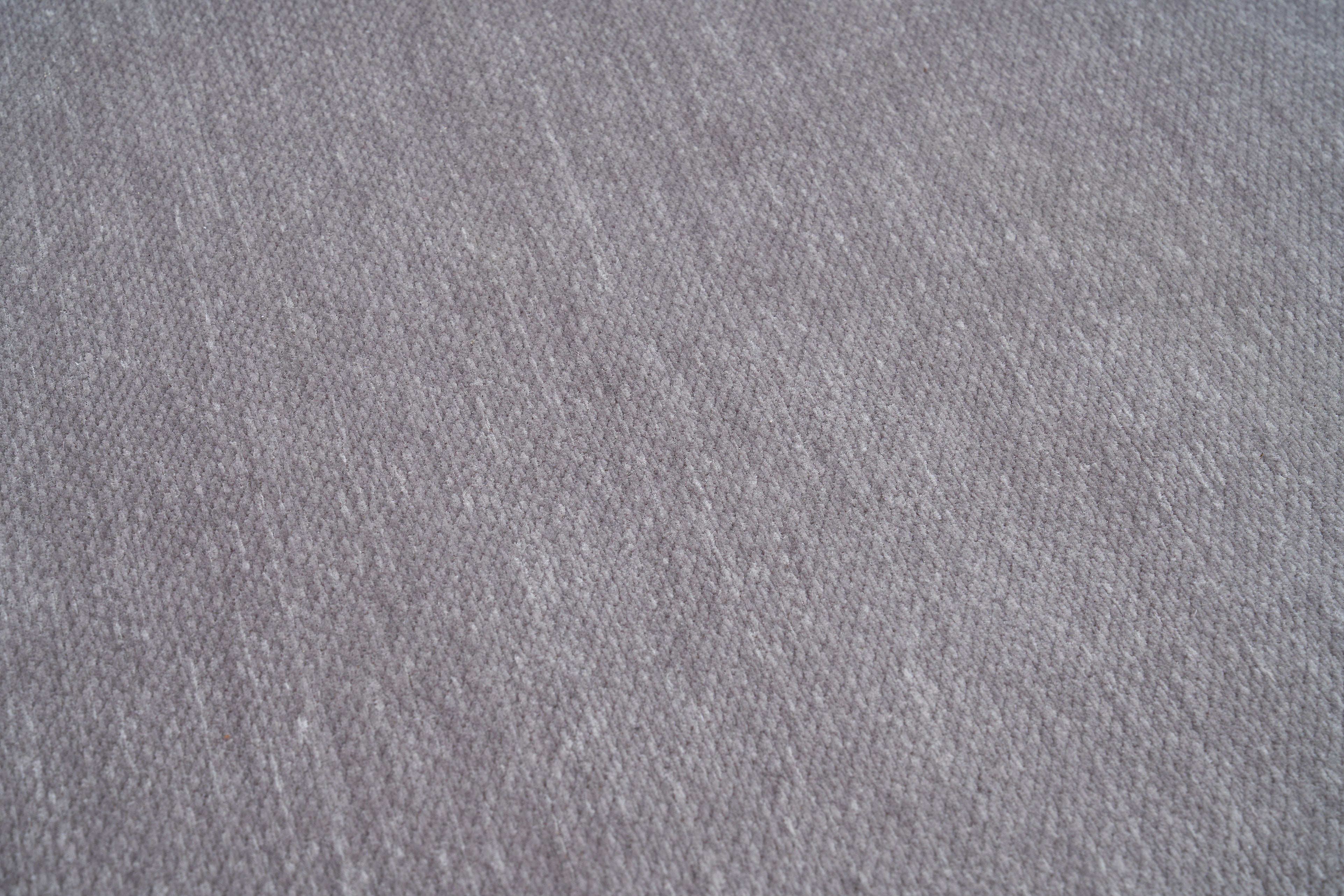 Tapis gris clair, tissage serré, relief subtil, aspect tactile doux. Forme rectangulaire