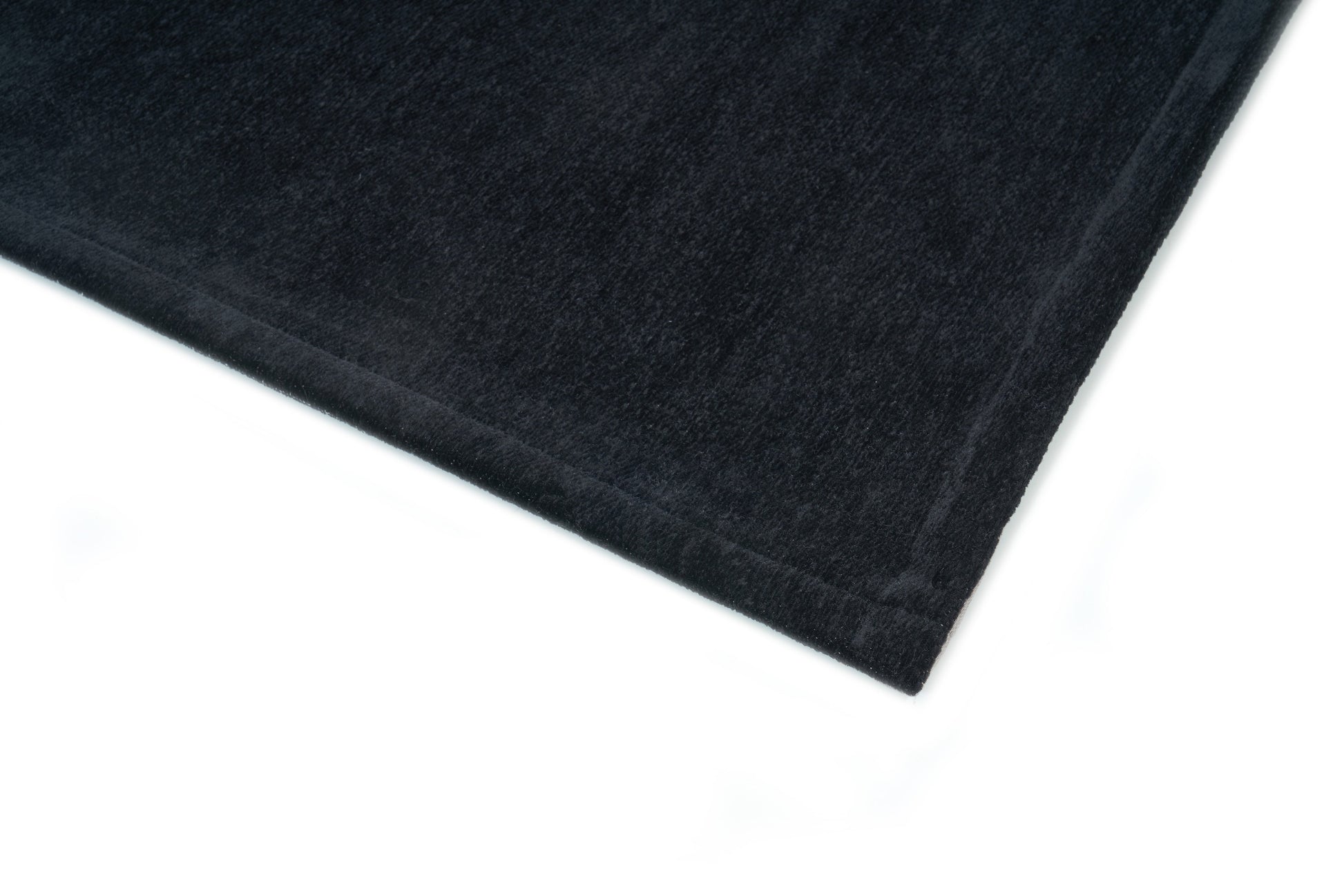 Bordure de tapis noir, finition cousue. Tissu texturé, ambiance sombre. Forme rectangulaire