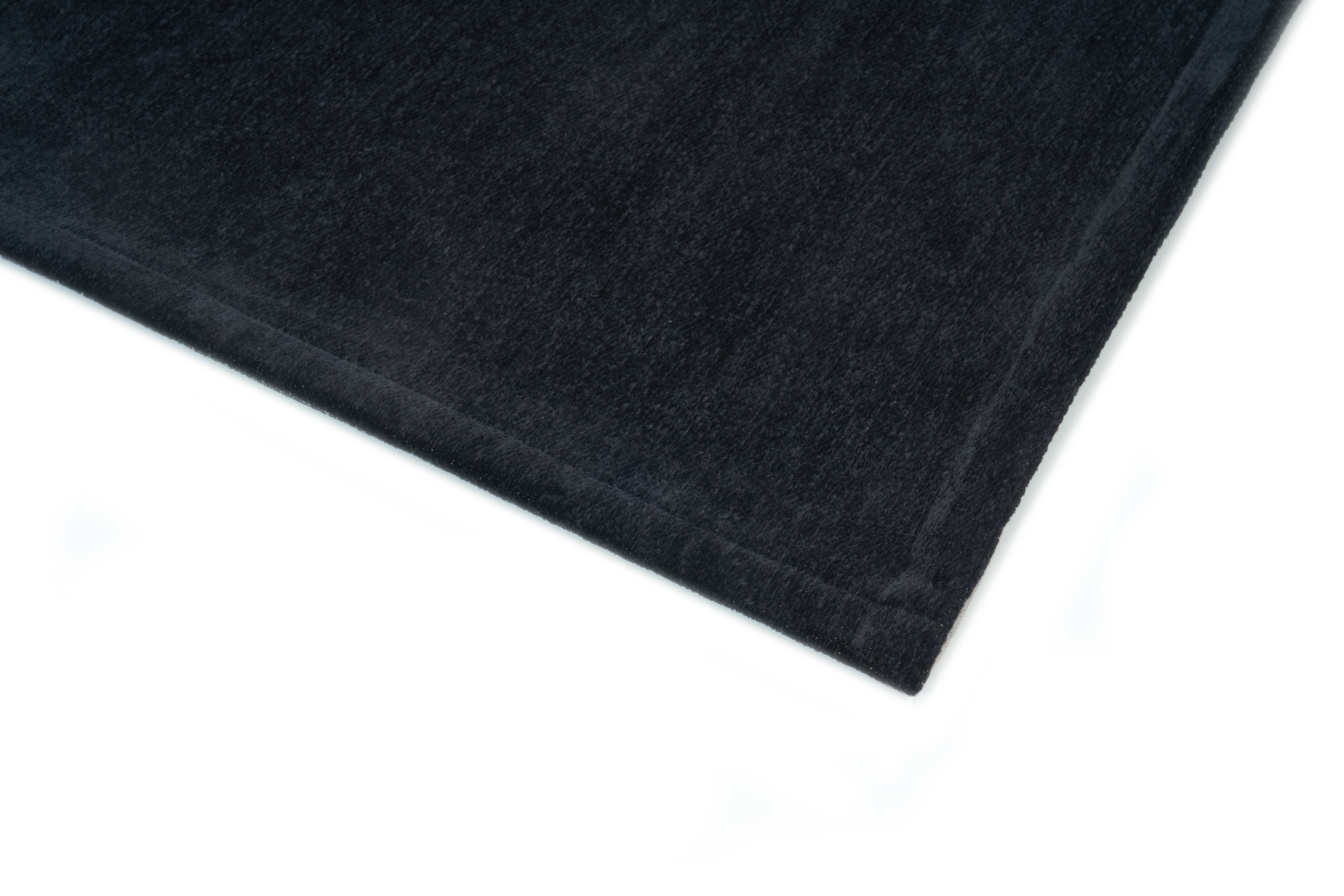 Bordure de tapis noir, finition cousue. Tissu texturé, ambiance sombre. Forme rectangulaire