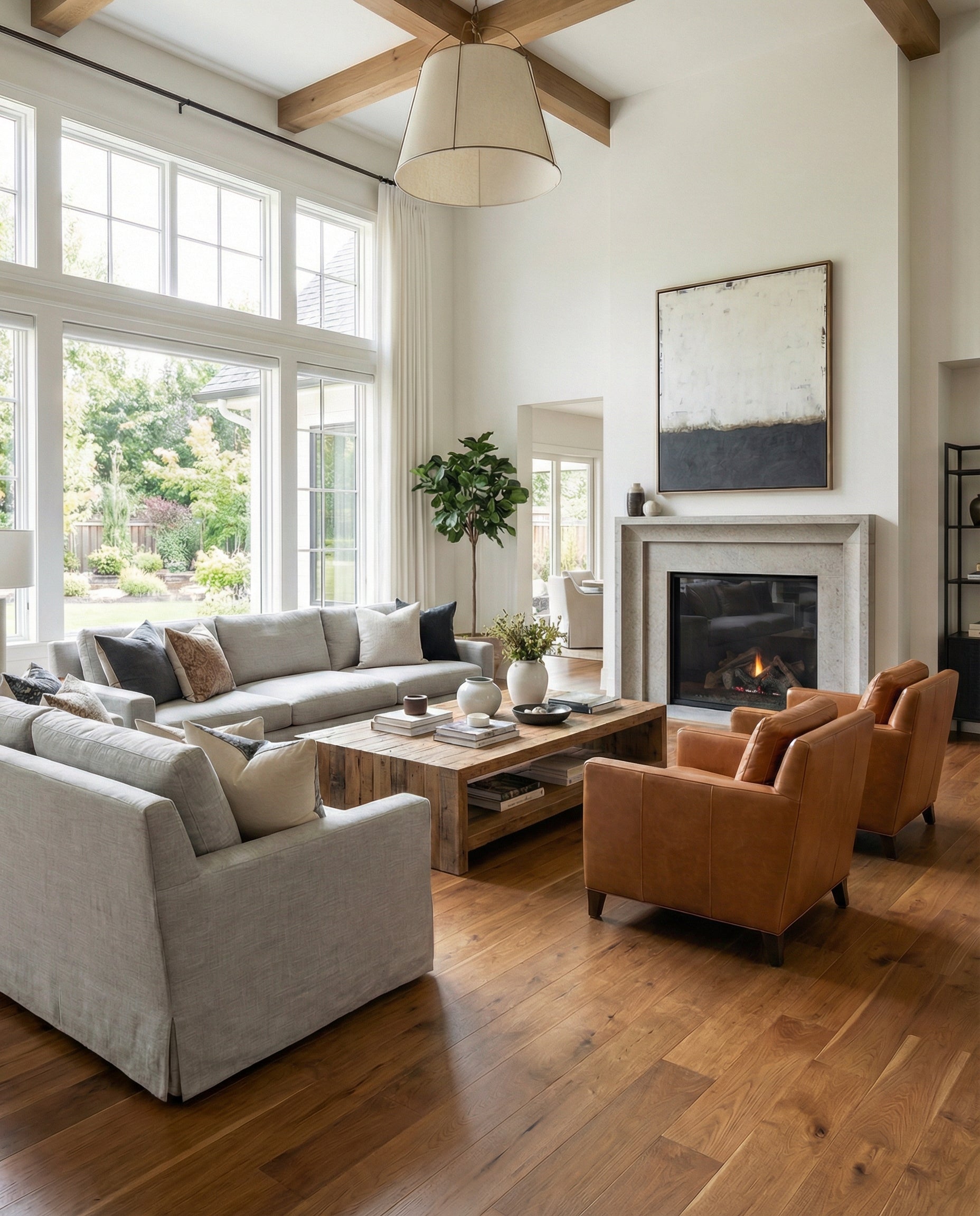 Pièce lumineuse avec plancher de bois franc. Canapés gris, fauteuils cuir, cheminée, tableau abstrait. Espace à transformer